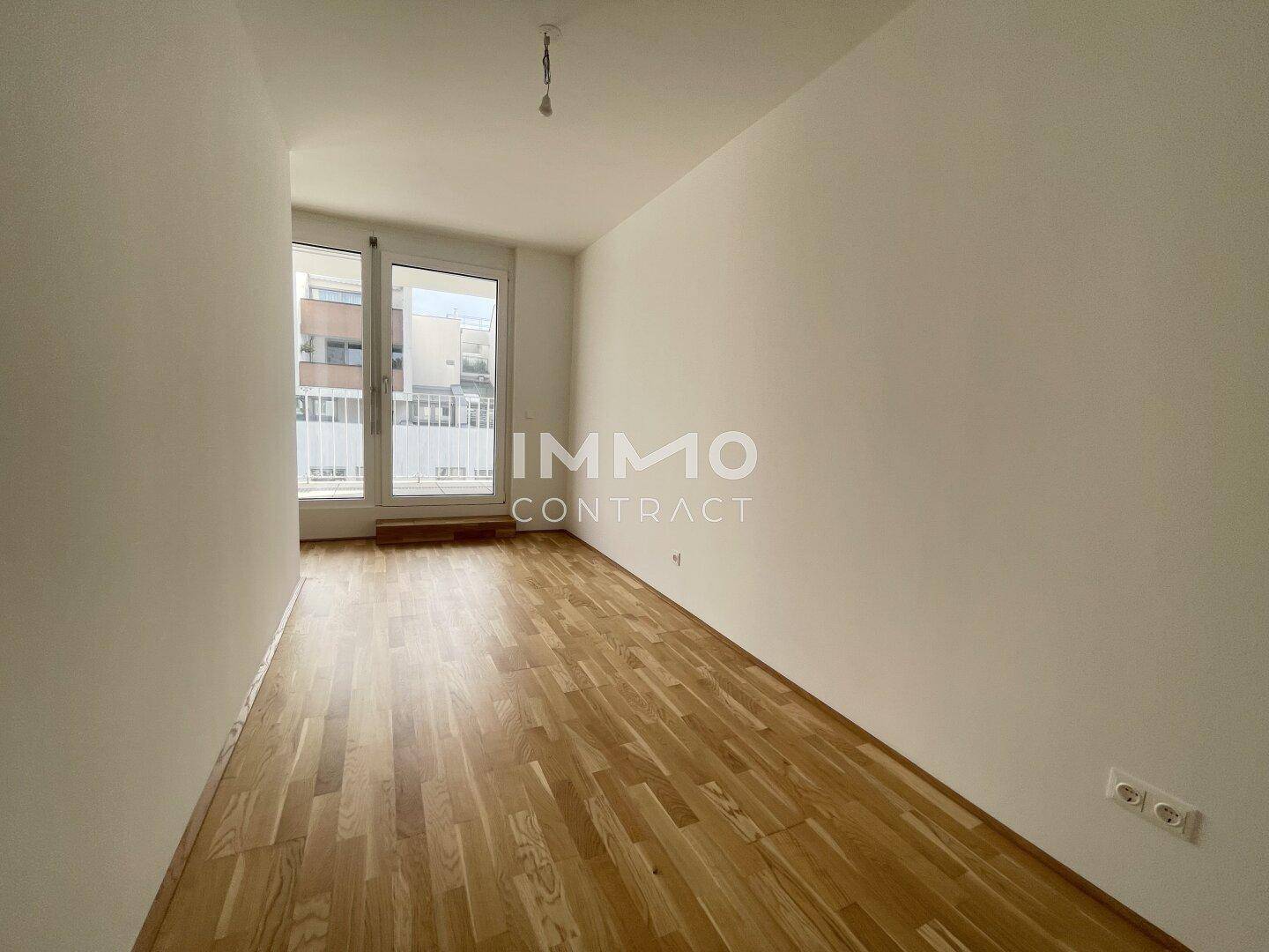 Gemütliches Schlafzimmer mit Holzboden und großen Fenstern, die viel Tageslicht hereinlassen.