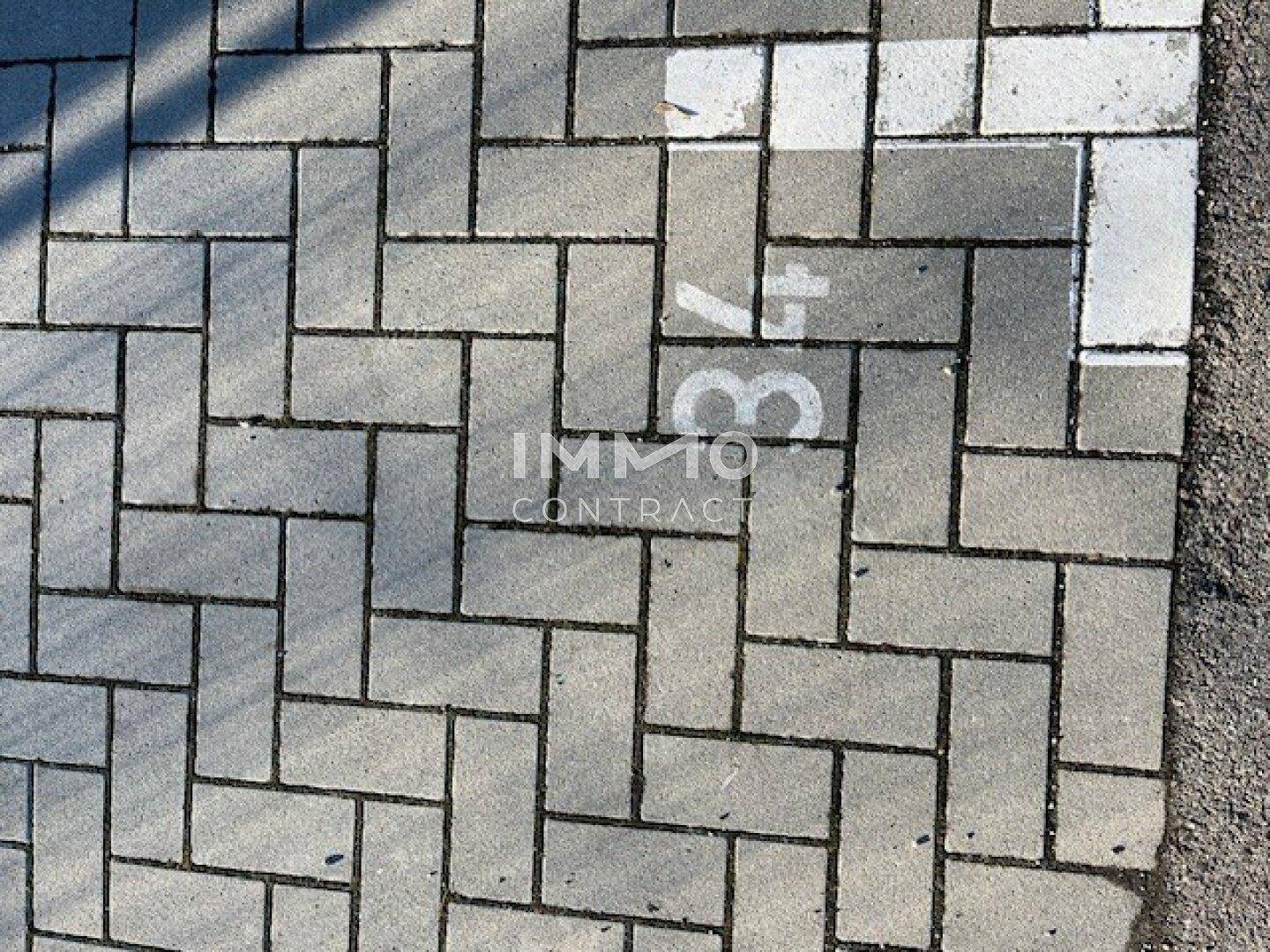 Nahaufnahme von Pflastersteinen auf einem Parkplatz, markiert mit der Stellplatznummer 37.
