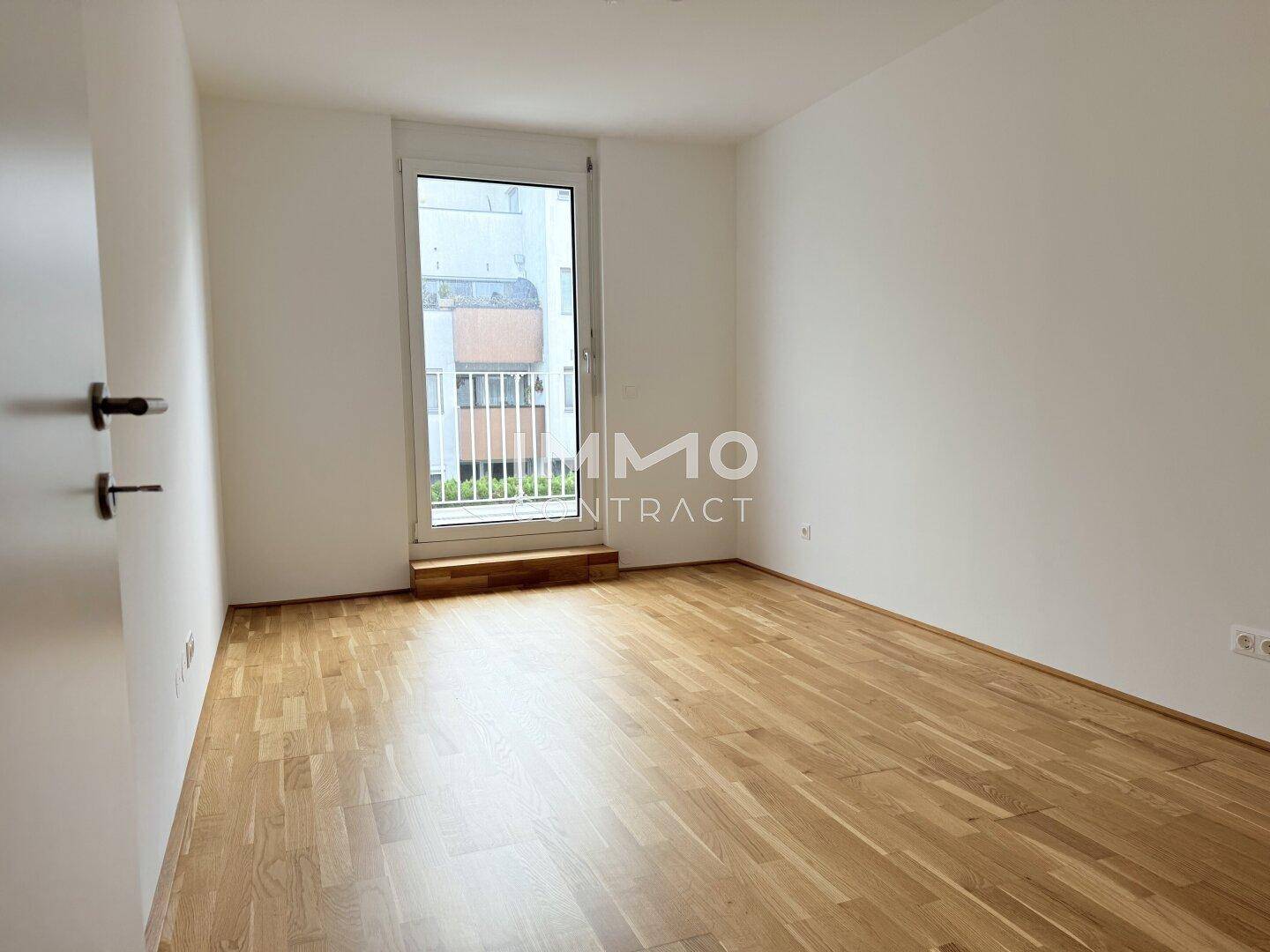 Geräumiges Schlafzimmer mit Holzboden und Fensterfront, ideal für viel Tageslicht.