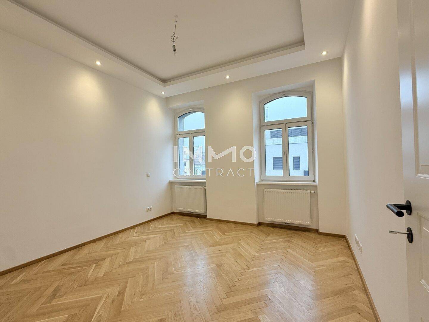 Geräumiges, helles Zimmer mit Fischgrätparkett und modernen Einbaustrahlern in der Decke.