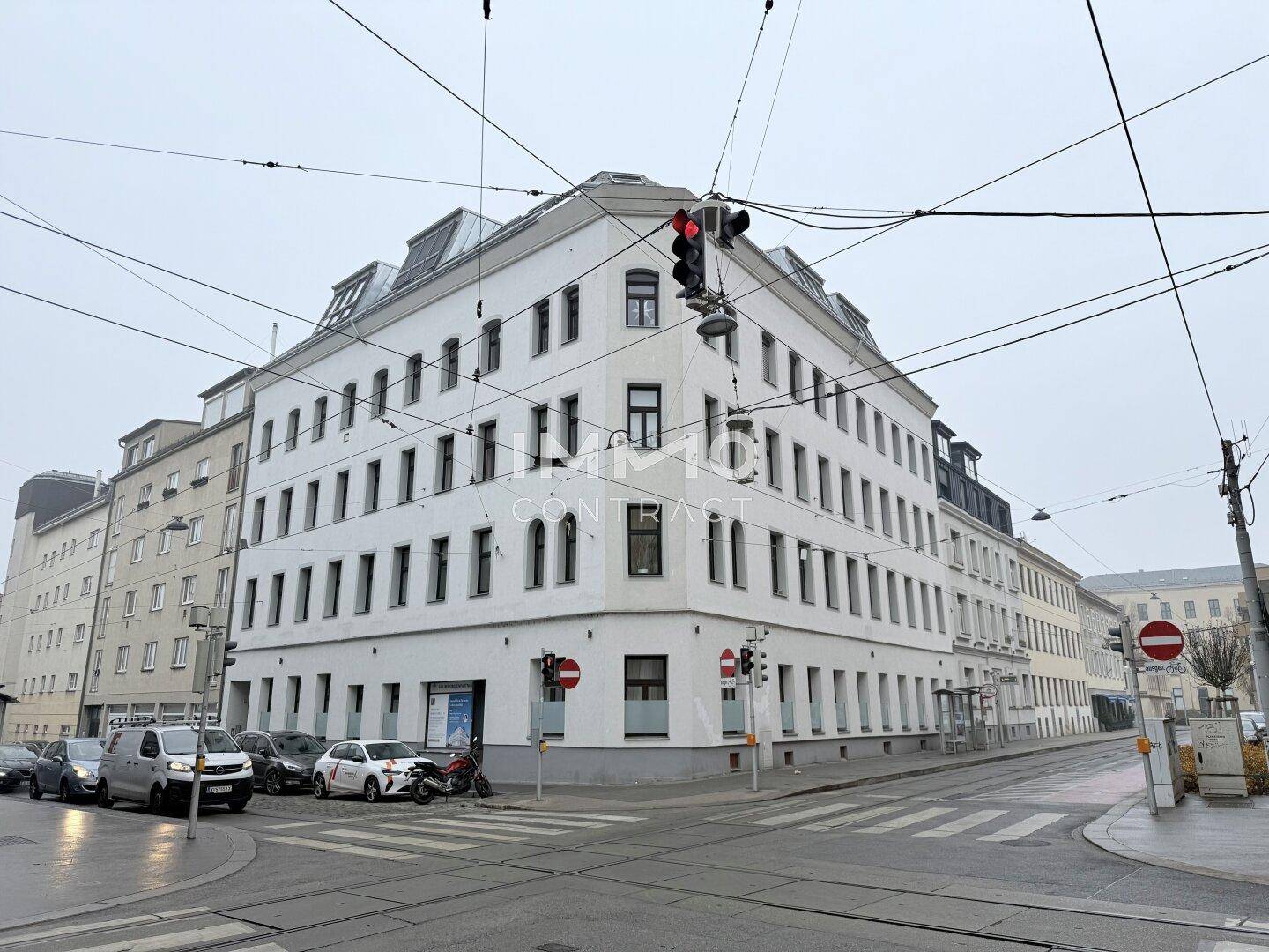 Historisches Eckgebäude in der Stadt mit vielen Fenstern und Mansarddach.