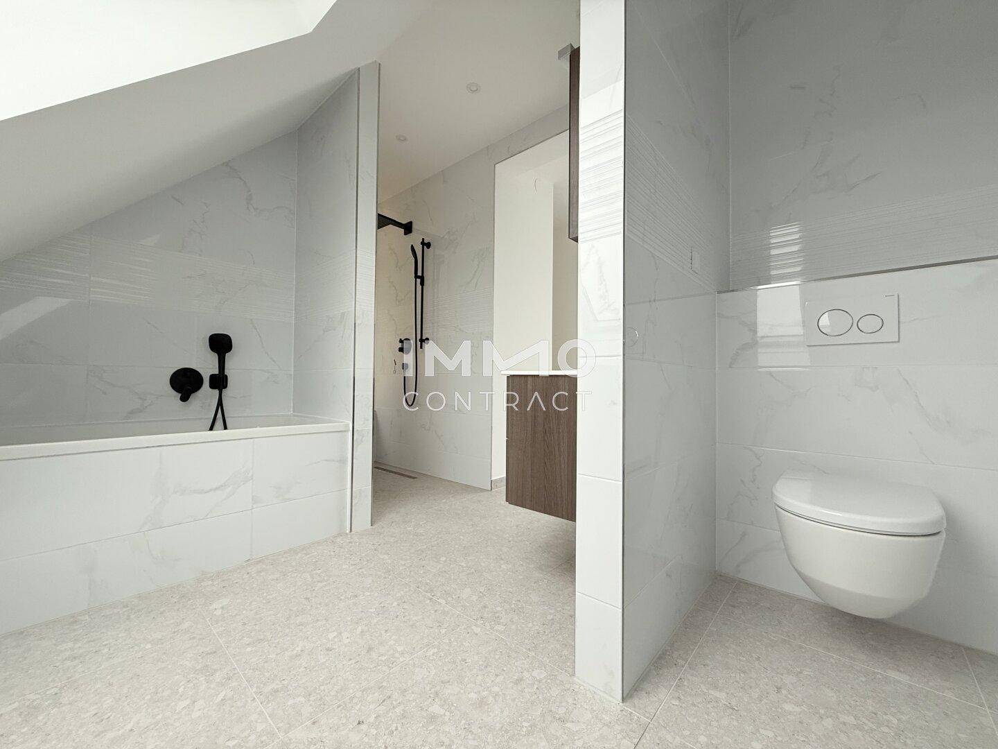 Modernes Badezimmer mit Badewanne, Dusche und wandhängendem WC, in hellen Marmorfliesen.