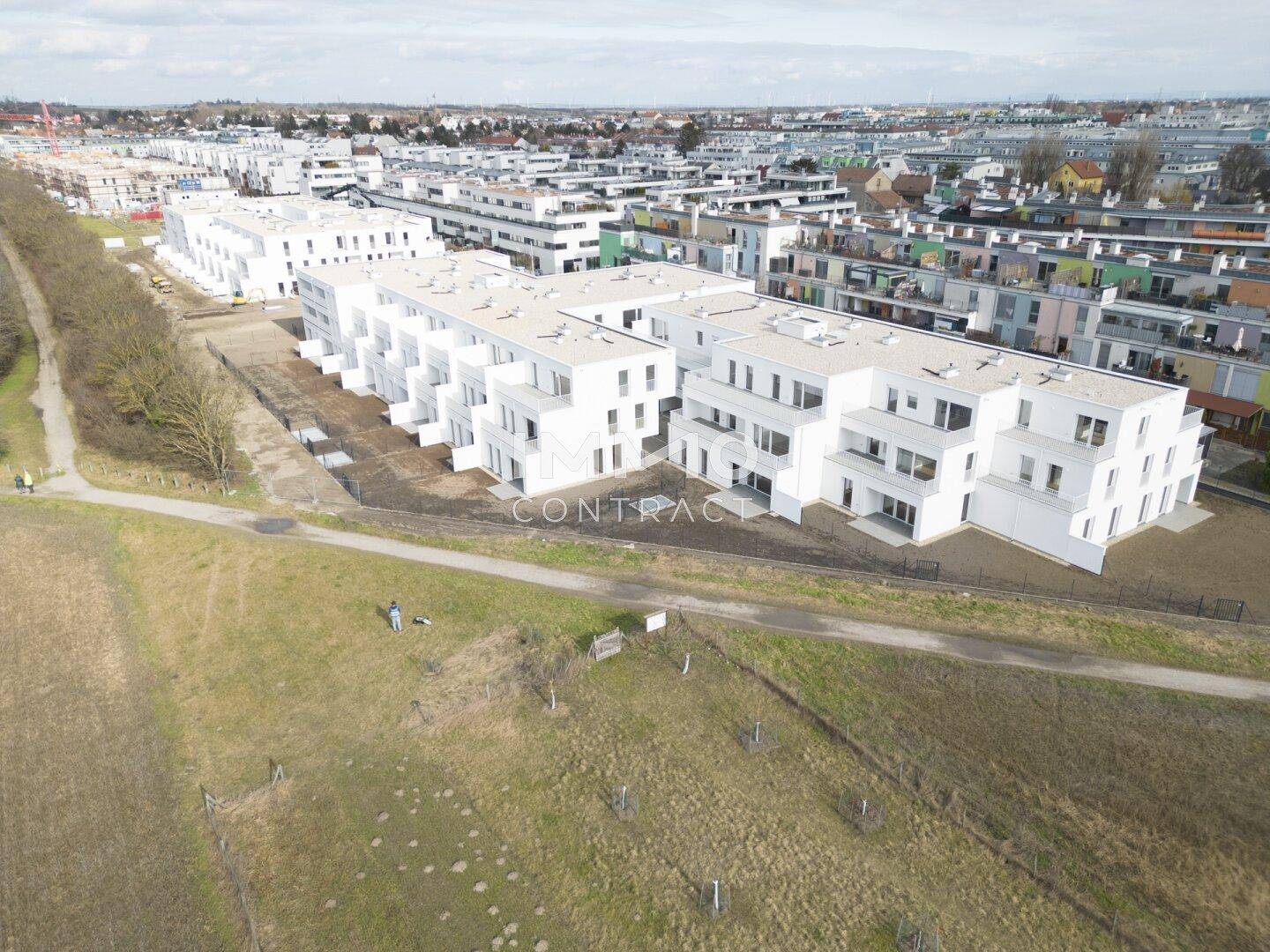 Weitläufige Luftaufnahme eines modernen Wohnkomplexes mit angrenzenden Grünflächen.
