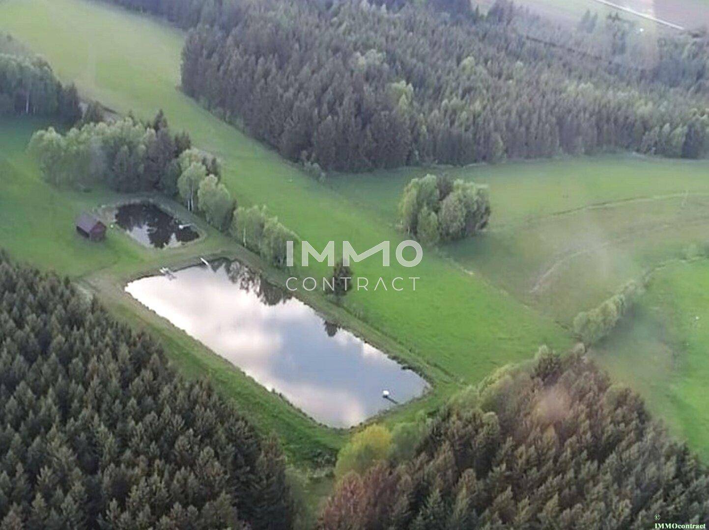 Panoramablick aus der Vogelperspektive auf eine ländliche Gegend mit Wasserflächen und Waldgebieten.