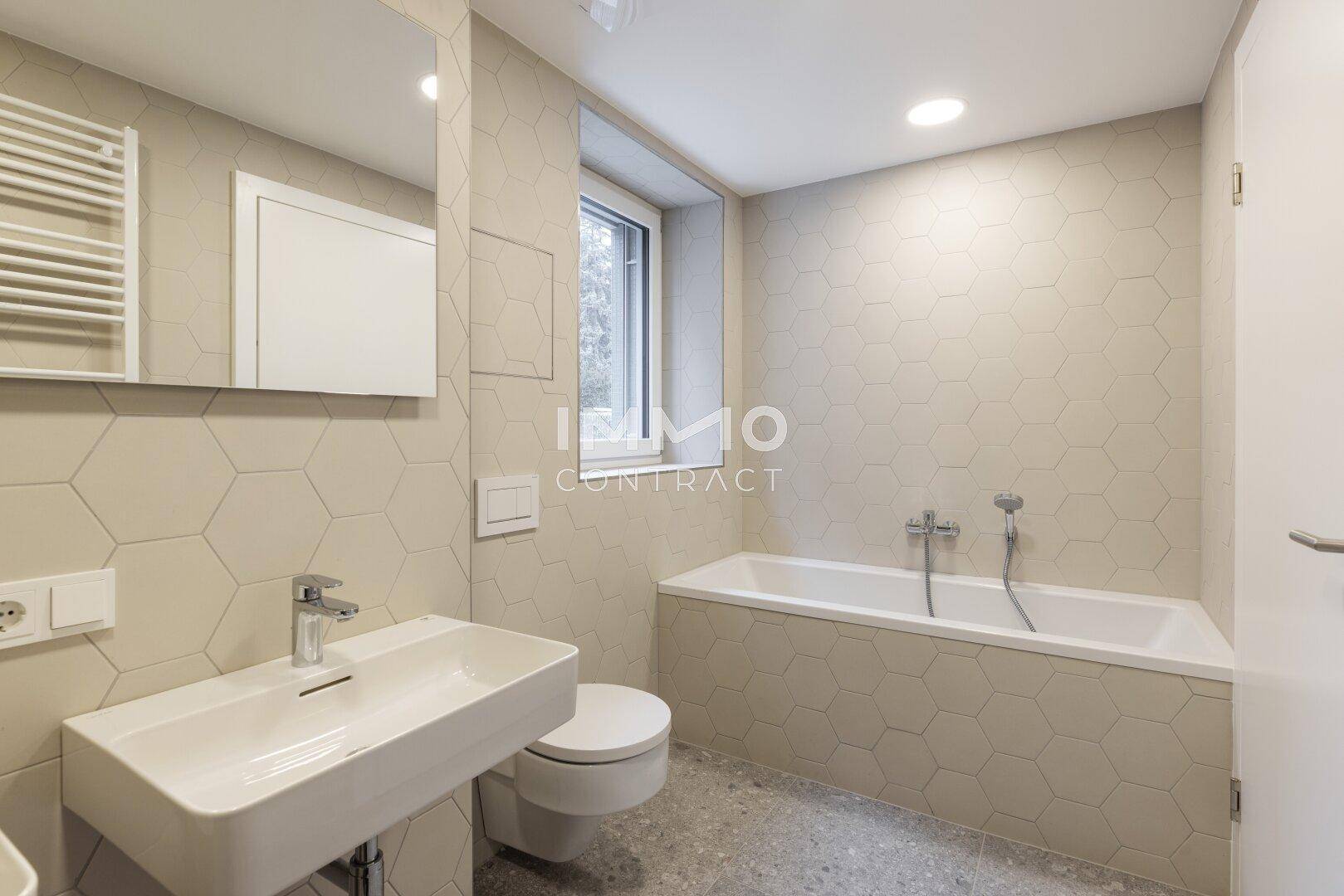 Modernes Badezimmer mit Badewanne, Einzelwaschbecken und sechseckigen Fliesen.