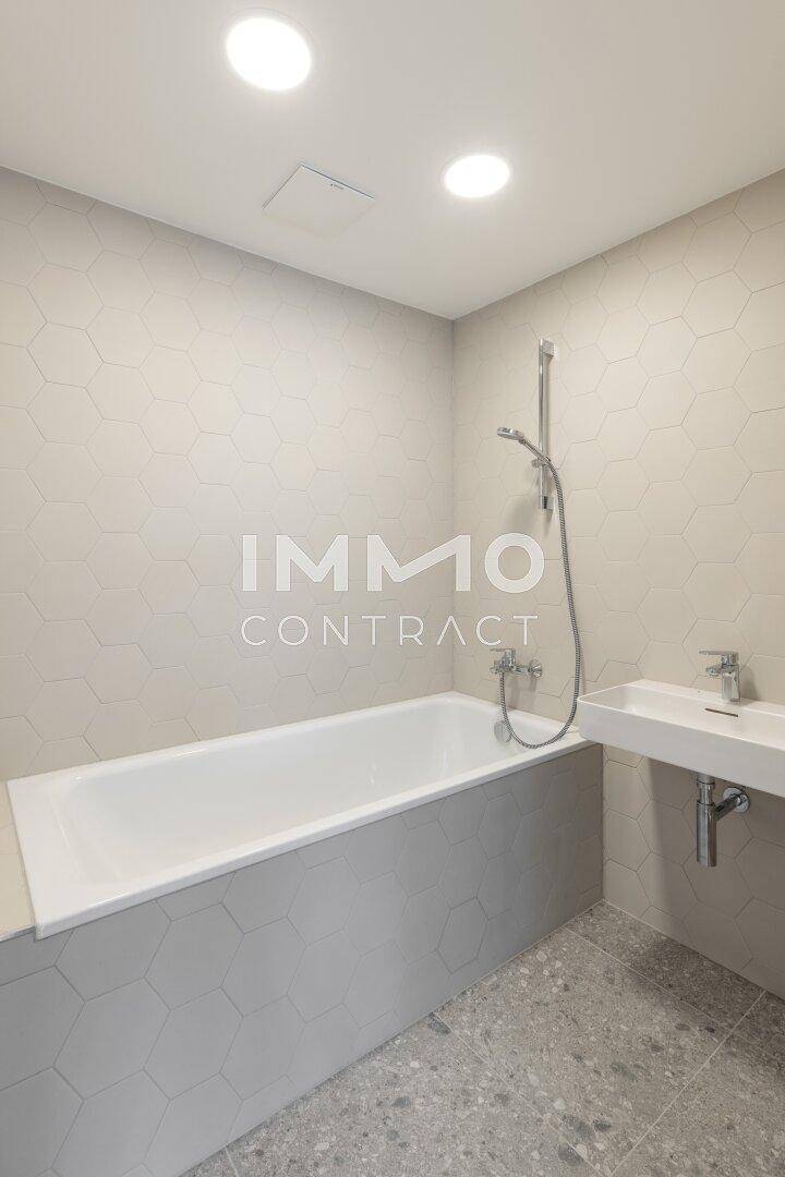 Modernes Badezimmer mit Badewanne, Einzelwaschbecken und stilvollen sechseckigen Wandfliesen.