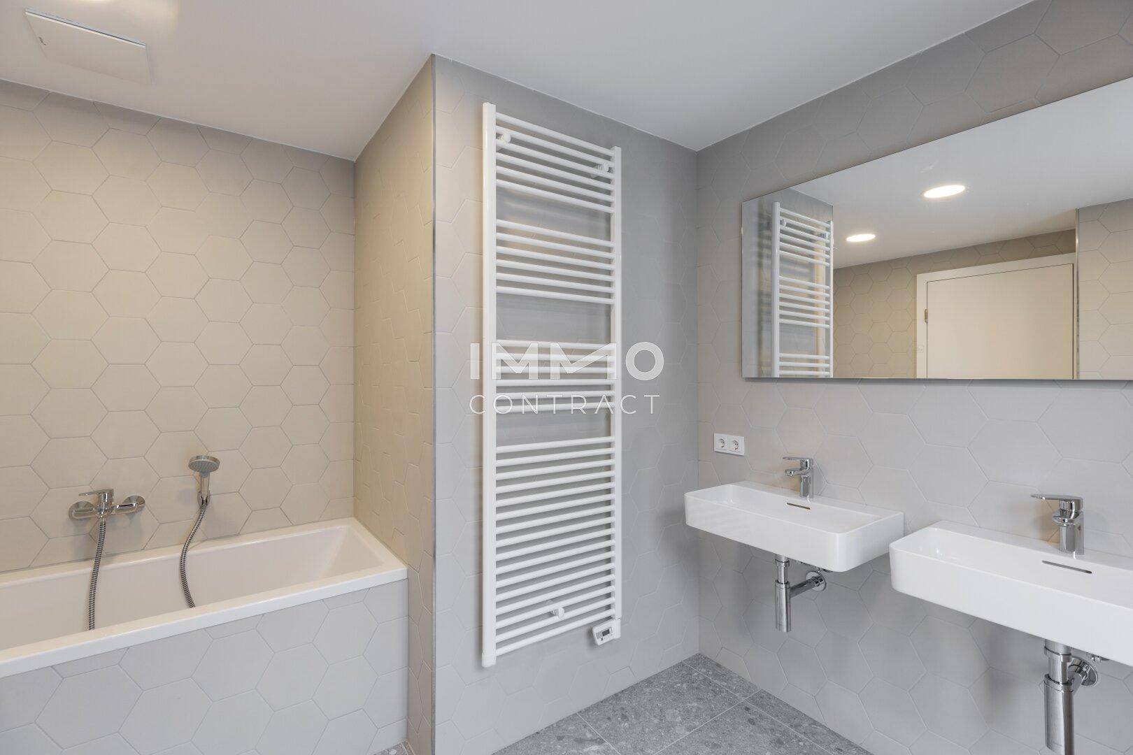 Elegantes Badezimmer mit Badewanne, Doppelwaschbecken und einem beheizten Handtuchhalter.