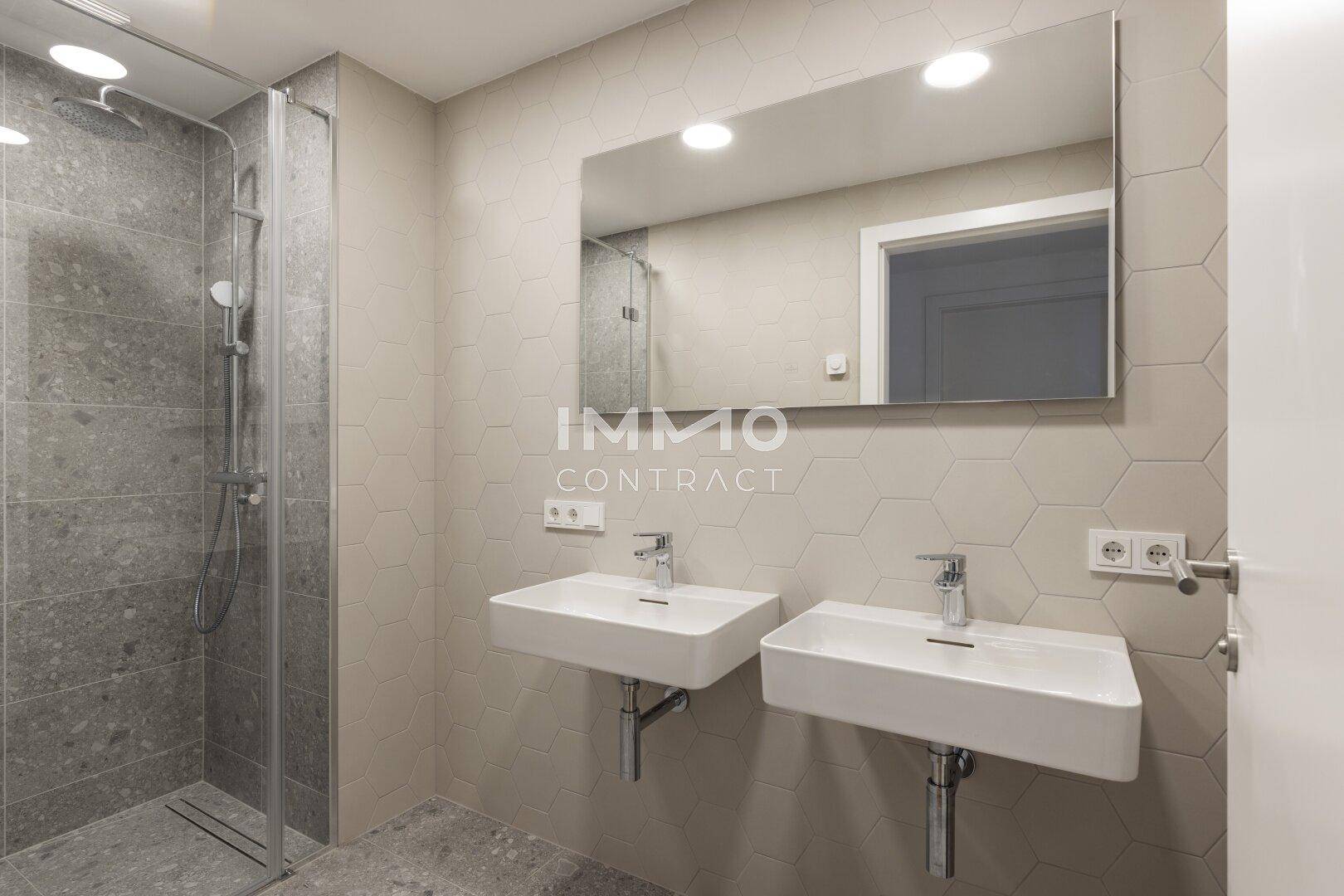 Modernes Badezimmer mit zwei Waschbecken, großem Spiegel und einer begehbaren Dusche.