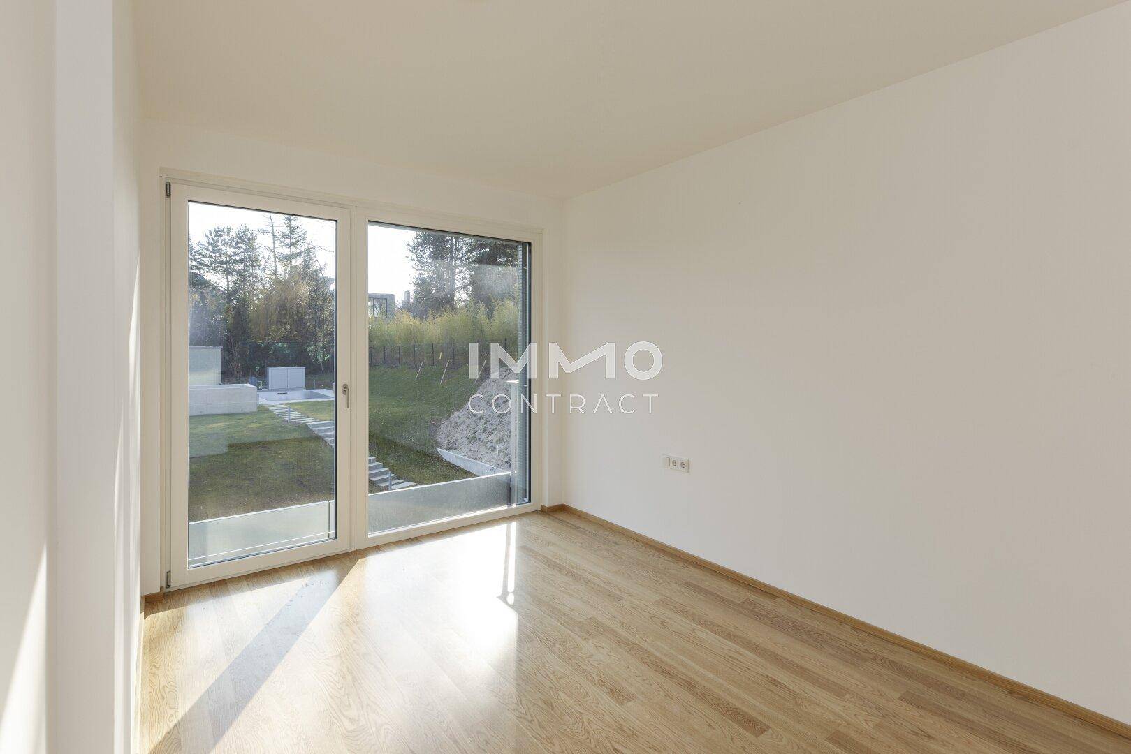 Helles Schlafzimmer mit Holzboden und Blick ins Grüne durch große Fenster, sehr ruhig gelegen.