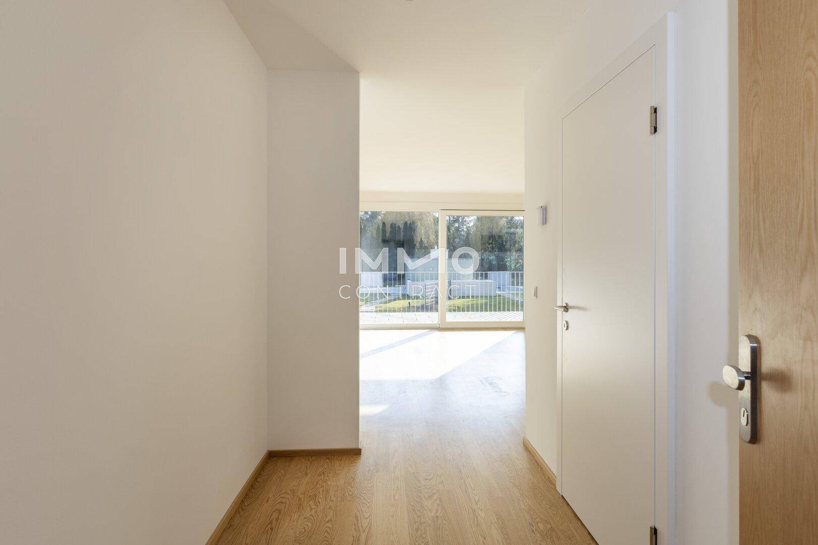 Heller Flur mit Holzboden, der zu einem lichtdurchfluteten Wohnbereich führt und einladend wirkt.