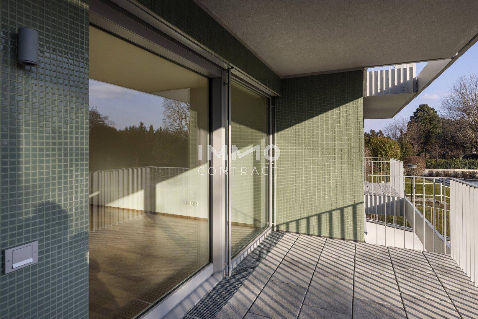 Geräumiger Balkon mit Fliesenboden und Blick auf die grüne Umgebung, ideal zum Entspannen.