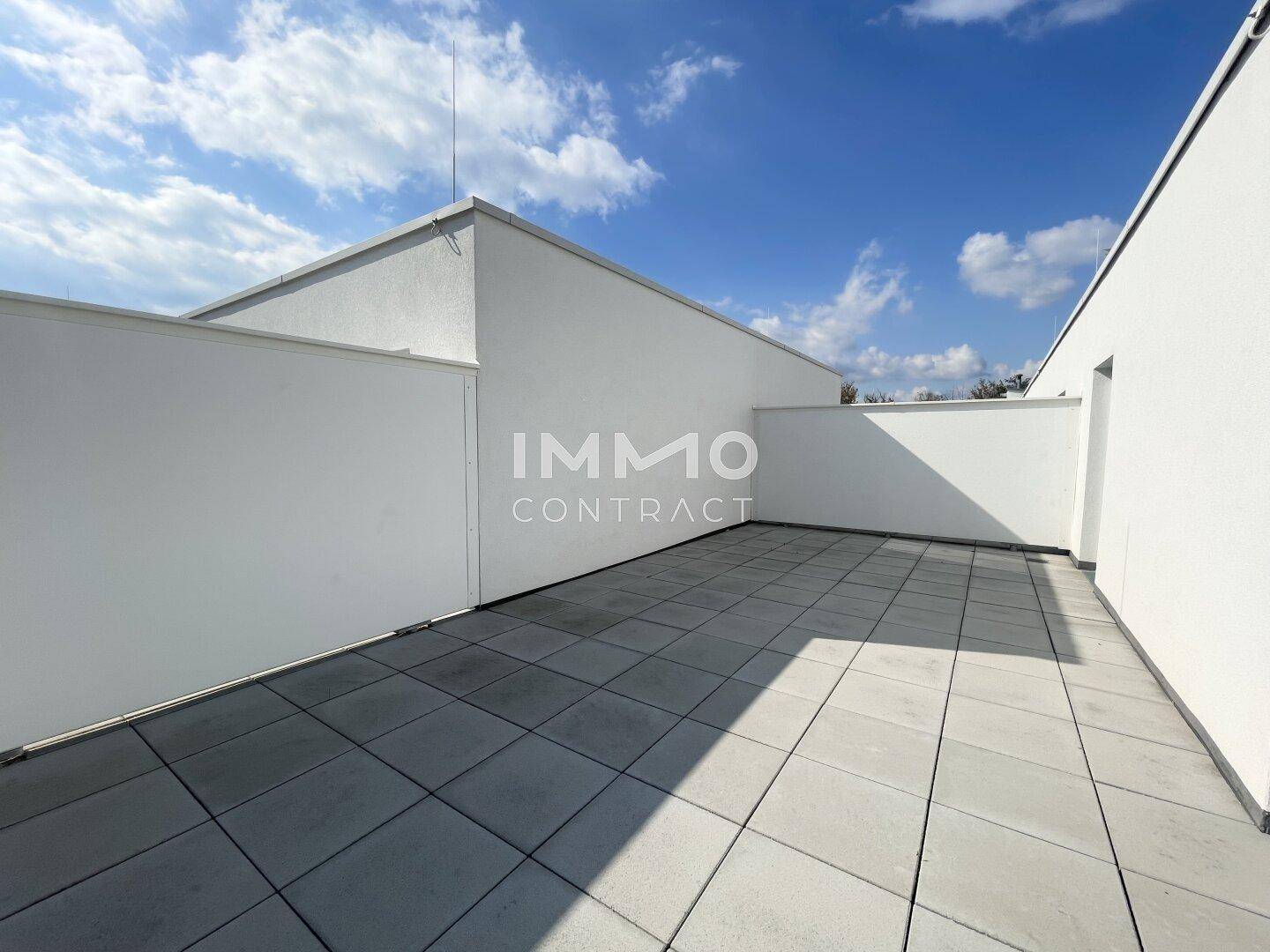 Ruhige Ecke einer modernen Dachterrasse mit weißen Wänden und Fliesenboden, bietet Privatsphäre im Freien.