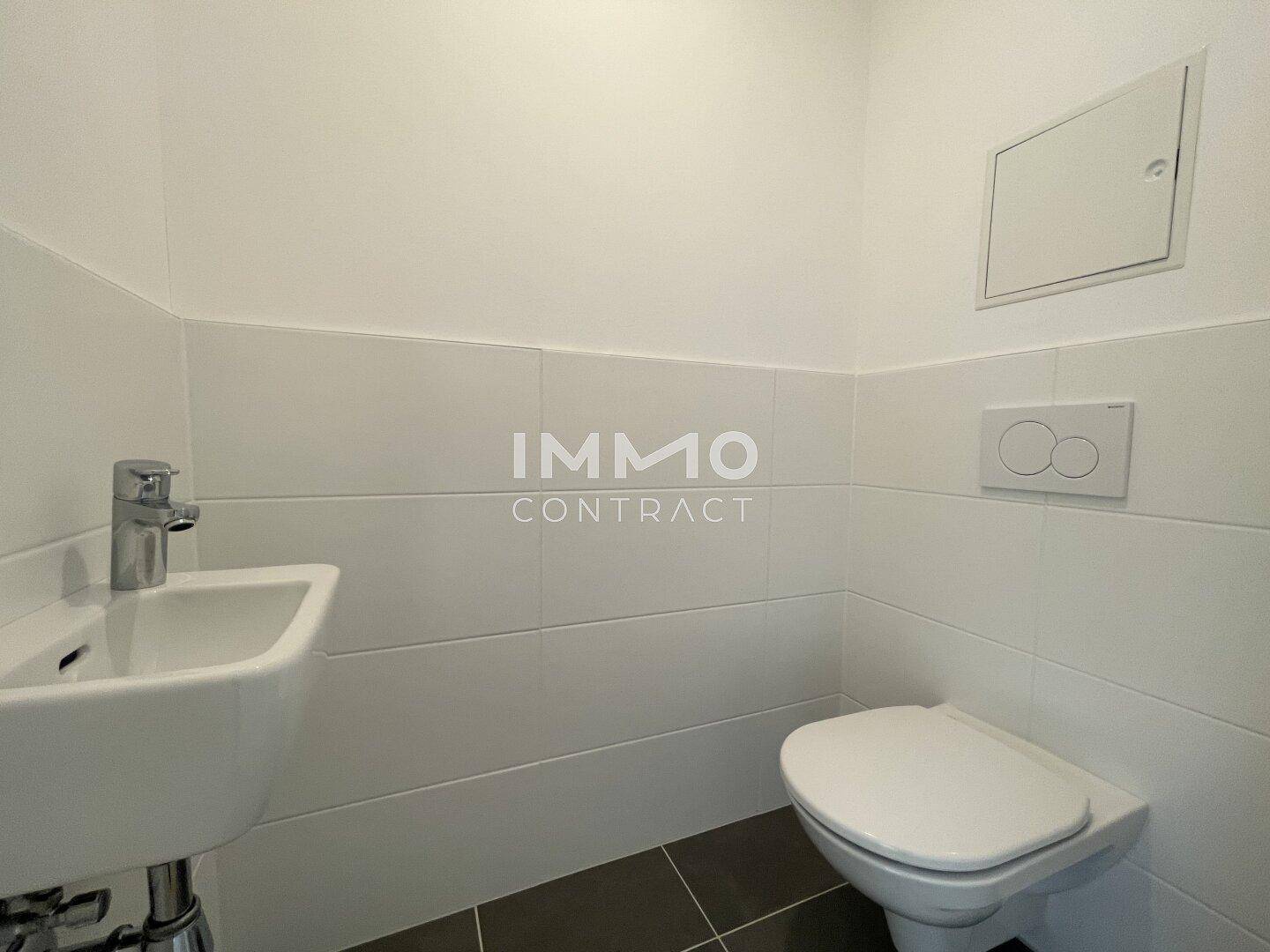 Kompakte und moderne Gästetoilette mit wandhängendem WC und kleinem Waschbecken, in neutralen Farben gehalten.