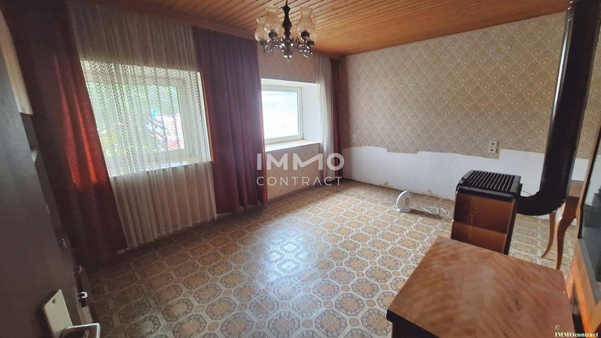 Wohnzimmer mit Holzdecke, gemustertem Boden und einem Holzofen für gemütliche Wärme.