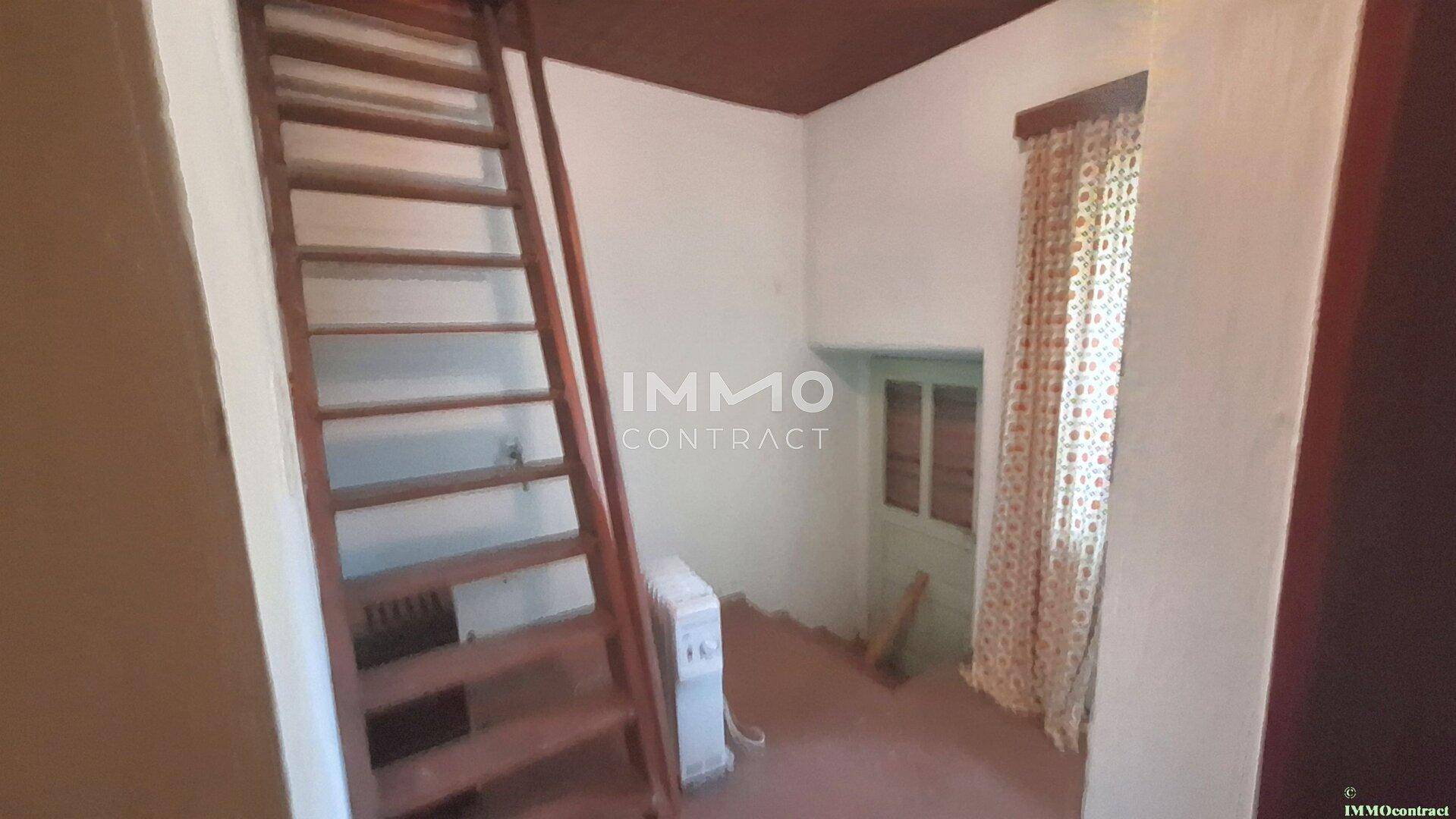 Kleiner Raum mit Holztreppe und Fenster, der als Durchgang oder Abstellraum dient.