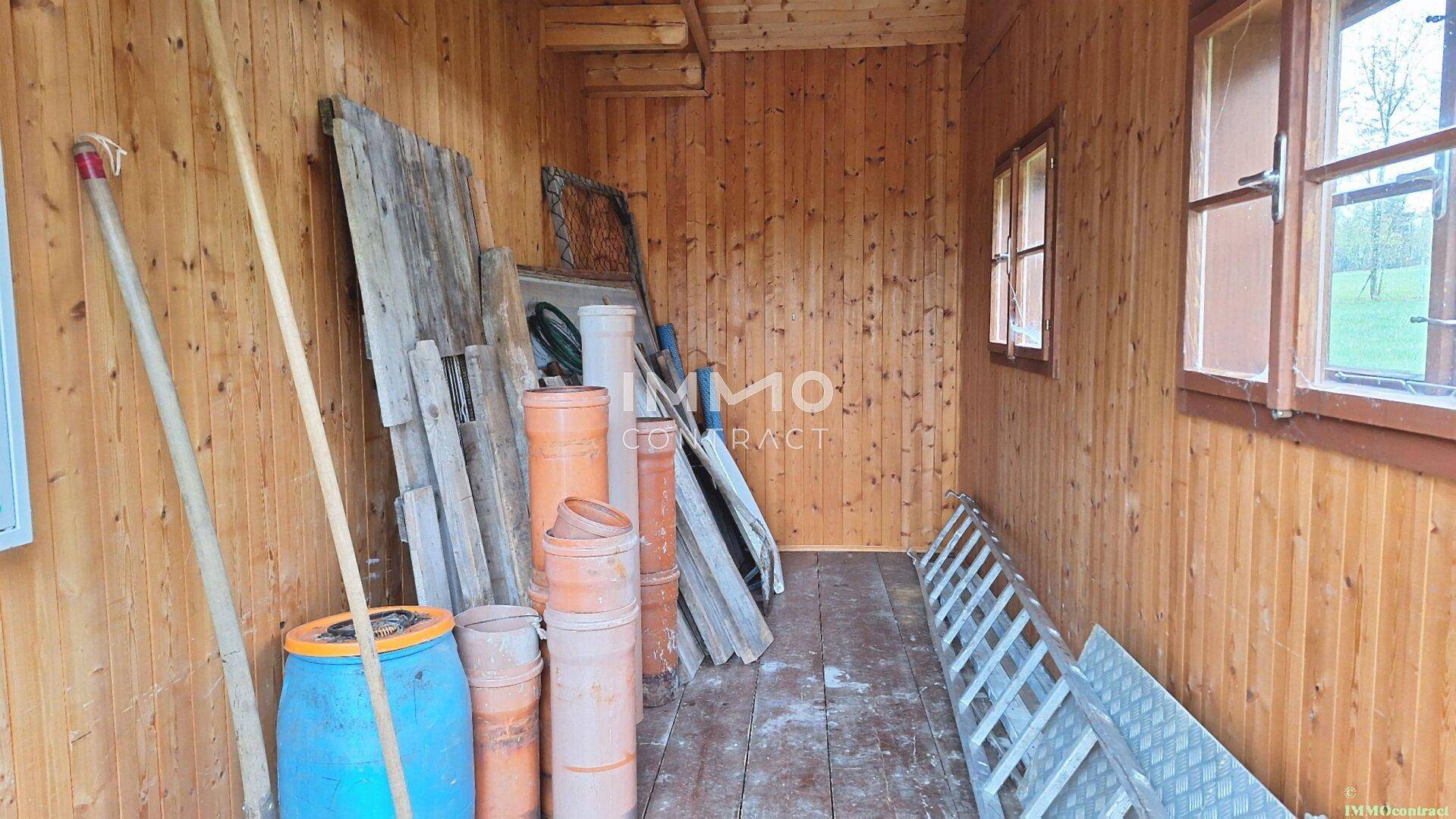 Einfacher Abstellraum in einem Holzhaus mit verschiedenen Werkzeugen und Baumaterialien.