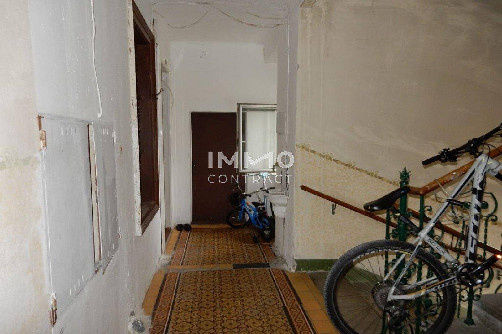 Flur im Treppenhaus mit Fahrrädern und gemusterten Fliesen auf dem Boden.