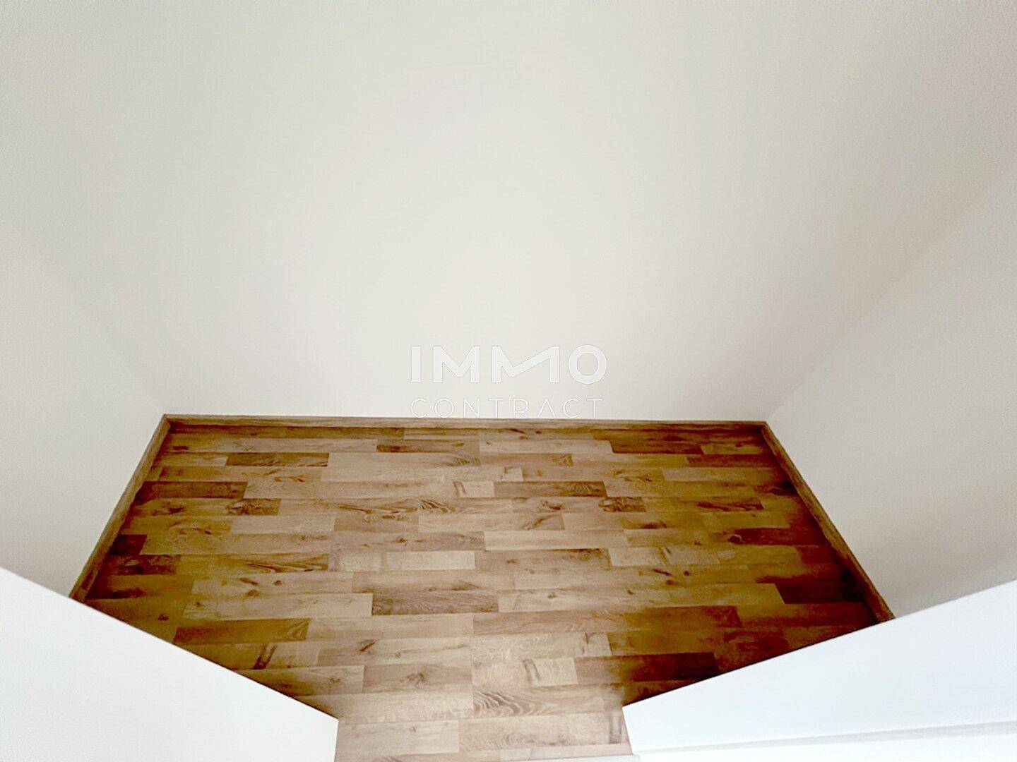 Detailaufnahme des Laminatbodens und der weißen Decke in einem hellen Innenraum.