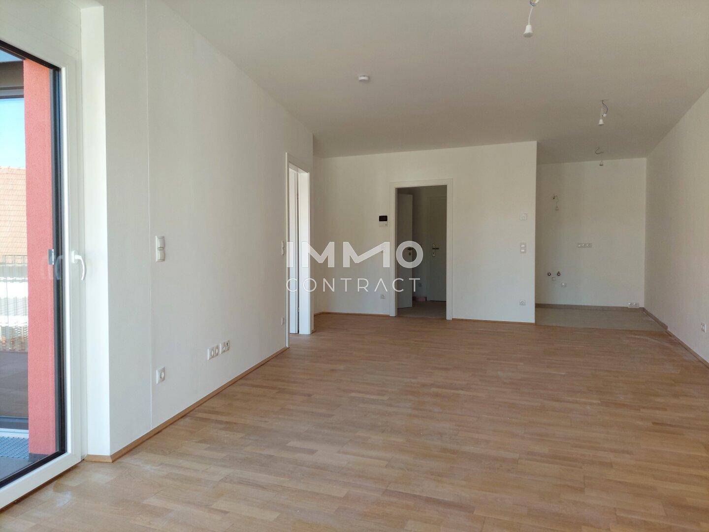 Helles, unmöbliertes Zimmer mit Parkettboden und Zugang zu einem Außenbereich, ideal für einen Wohnbereich.