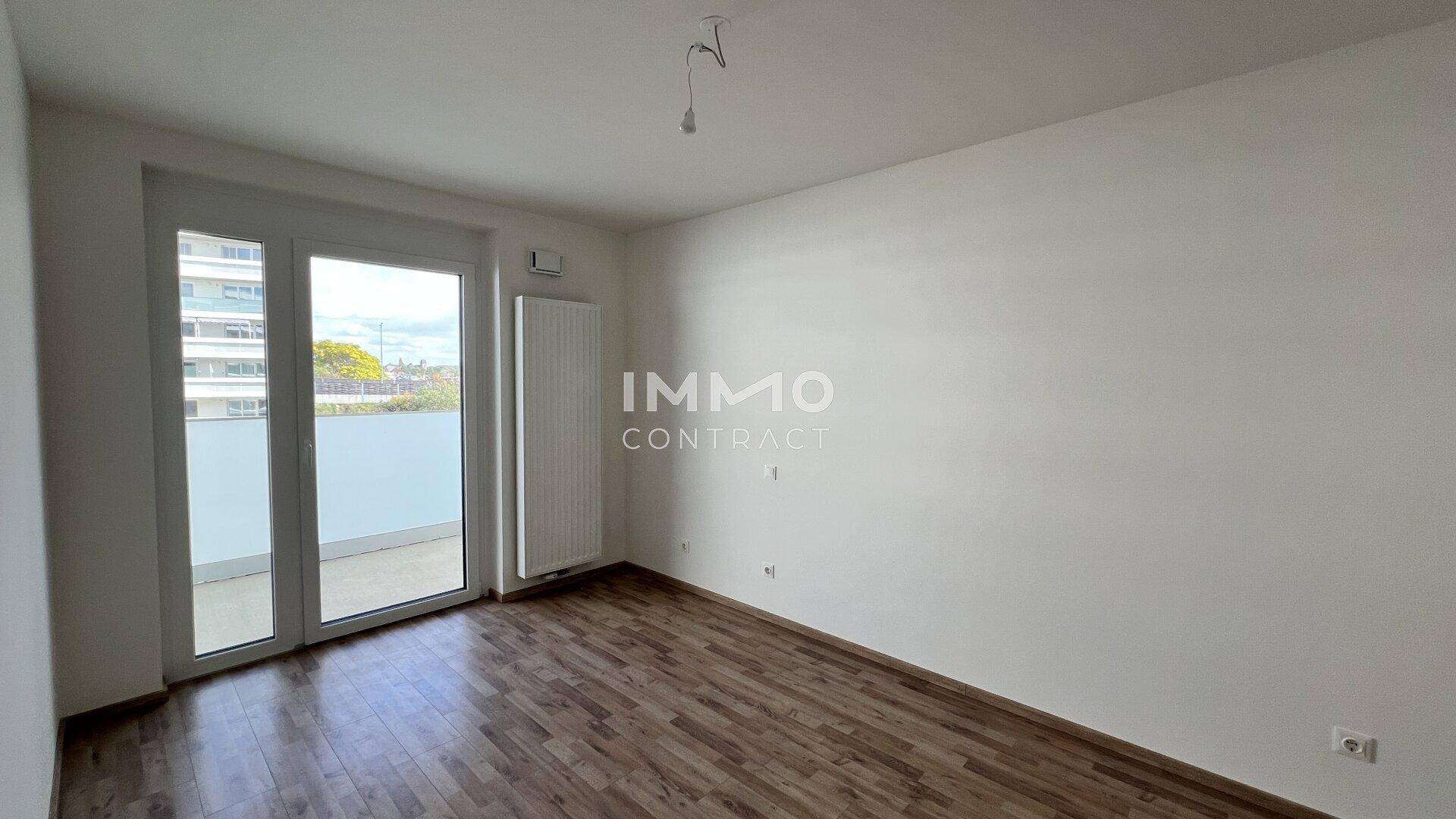 Helles Schlafzimmer mit Laminatboden und direktem Zugang zum Balkon.