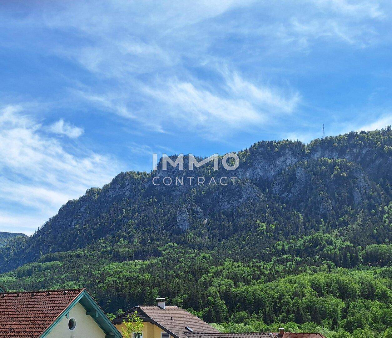 Atemberaubender Blick auf bewaldete Berge unter einem blauen Himmel mit Wolken.