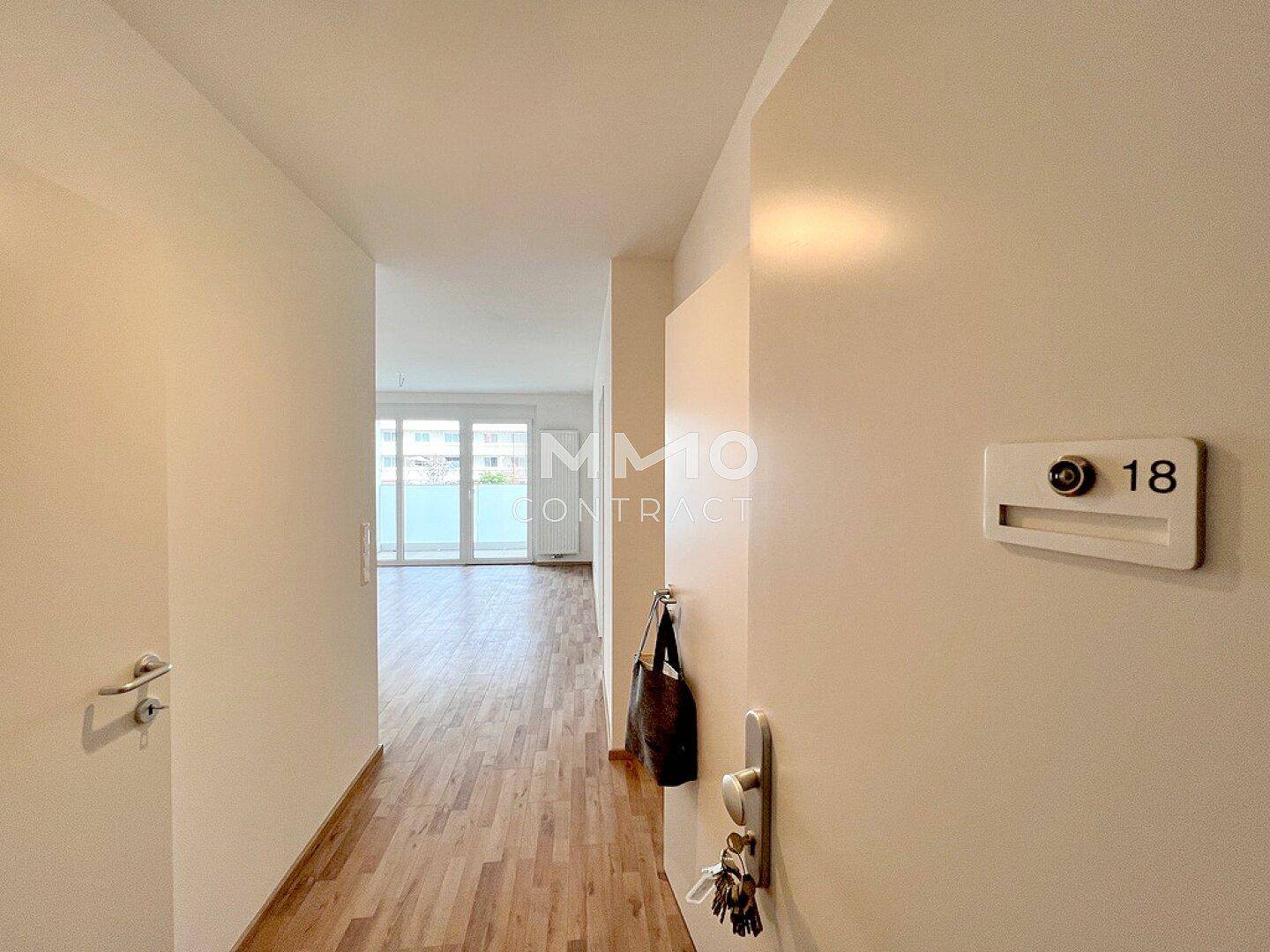 Heller Eingangsbereich mit Laminatboden und Blick in den Wohnbereich mit Balkonzugang.