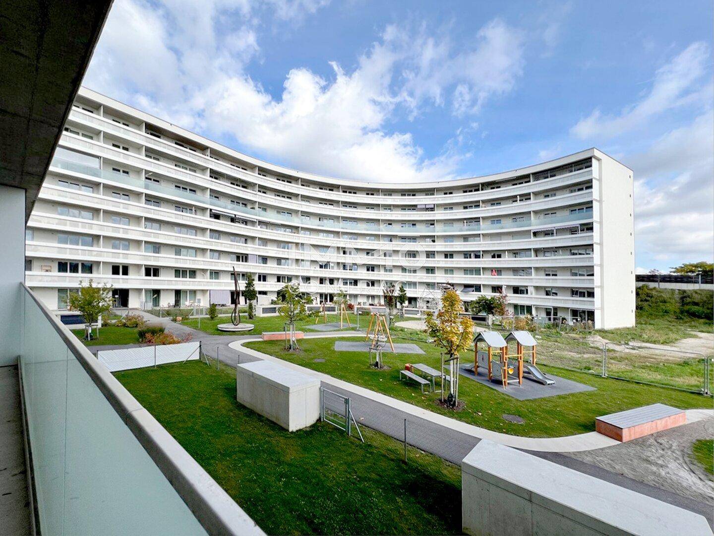 Großer begrünter Innenhof mit Spielplatz, umgeben von moderner Wohnbebauung.