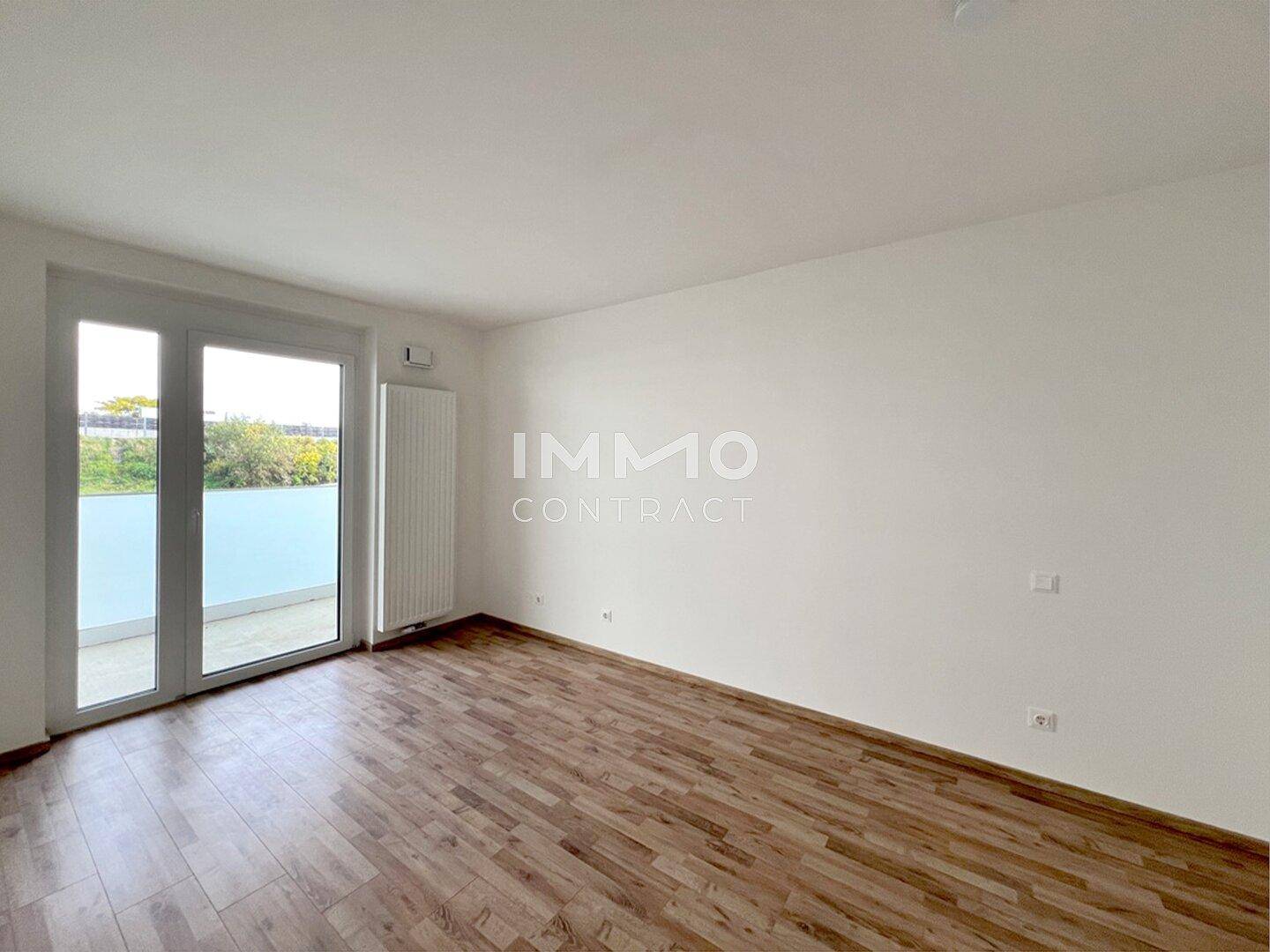 Helles Zimmer mit Laminatboden und Zugang zu einem Außenbereich, ideal als Schlaf- oder Arbeitszimmer.