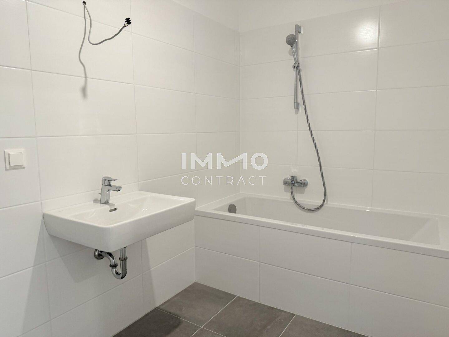 Modernes Badezimmer mit Badewanne, Waschbecken und großen weißen Wandfliesen.