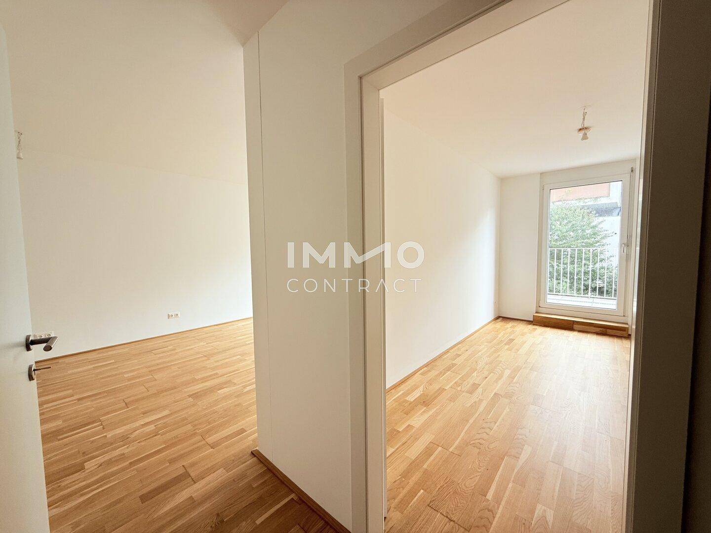 Heller Flur mit Holzboden, der zu einem weiteren, lichtdurchfluteten Zimmer führt.