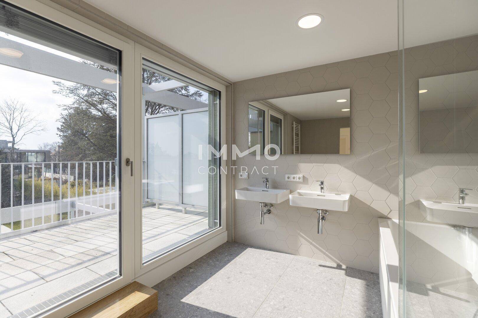 Modernes Badezimmer mit Badewanne, Doppelwaschbecken und großem Fenster zur Terrasse.
