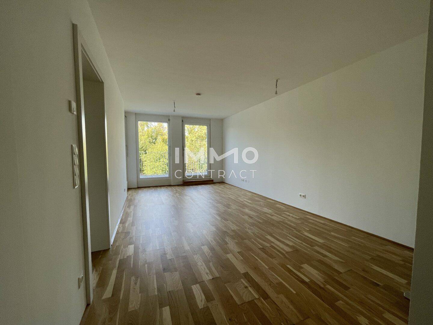 Helles, leeres Zimmer mit Parkettboden und großen Fenstern, bereit zur individuellen Gestaltung.