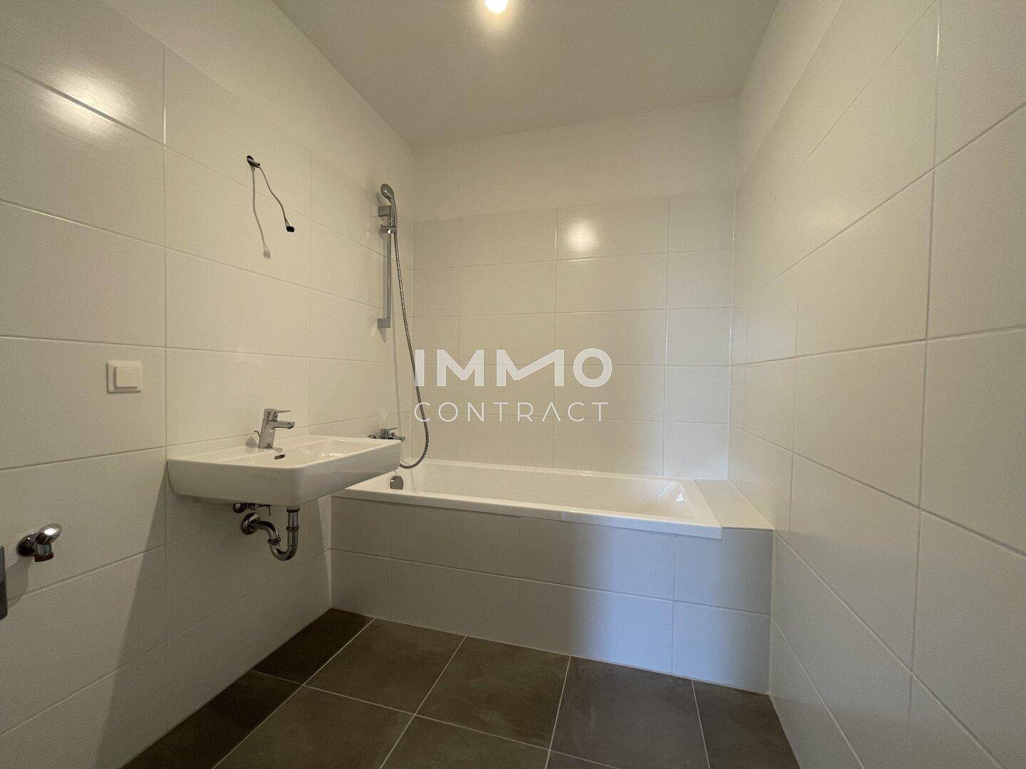 Modernes Badezimmer mit weiß gefliesten Wänden, Badewanne und Waschbecken, bereit zur Nutzung.