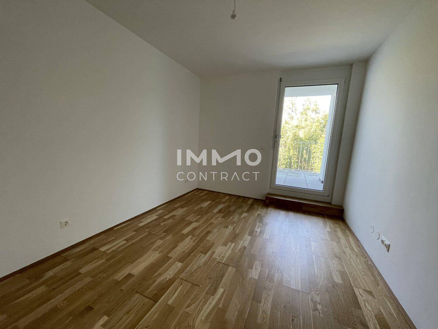 Helles Schlafzimmer mit Parkettboden und direktem Zugang zu einem sonnigen Balkon.