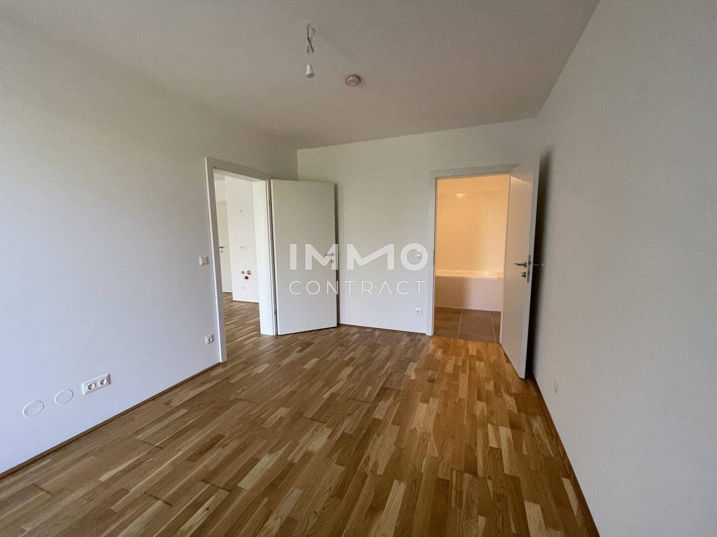 Leeres Zimmer mit Parkettboden und Zugang zu weiteren Räumen, ideal als Schlaf- oder Arbeitszimmer.
