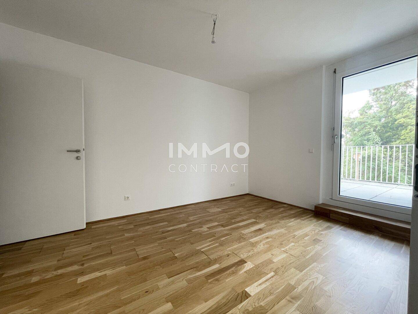 Schlafzimmer mit hellem Parkettboden und Zugang zu einem Balkon oder einer Loggia.
