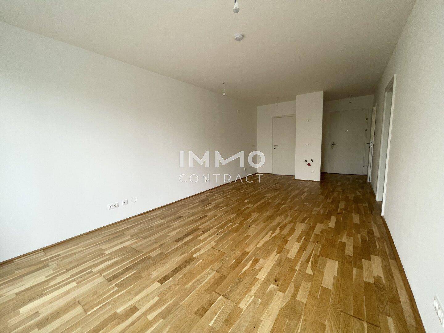 Heller Wohnraum mit Holzboden und weiß gestrichenen Wänden, bereit für individuelle Gestaltung.