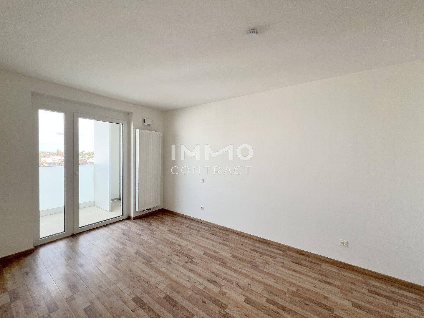 Helles Schlafzimmer mit Laminatboden und direktem Zugang zum Balkon.