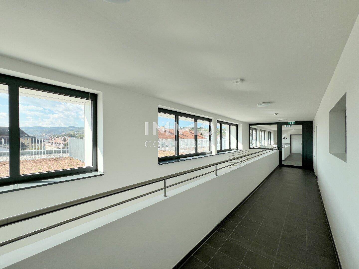Heller Gemeinschaftsflur mit großen Fenstern und Blick auf die Umgebung.