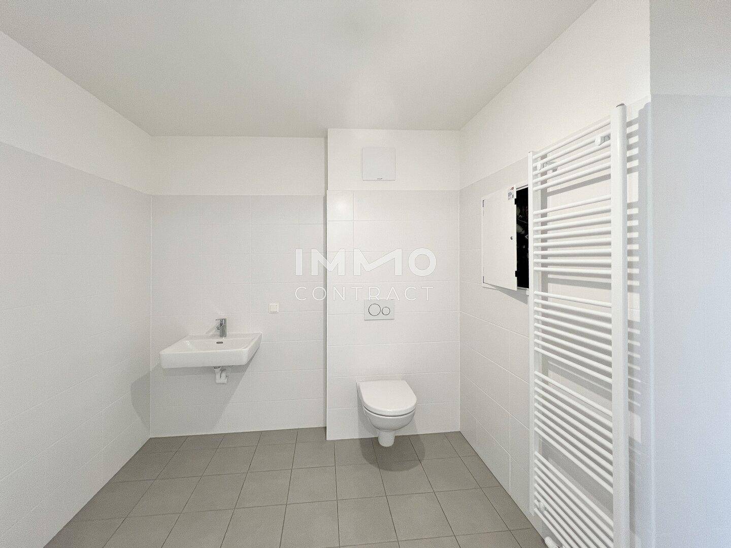 Modernes WC mit Wand-WC, Einzelwaschbecken und beheiztem Handtuchhalter.