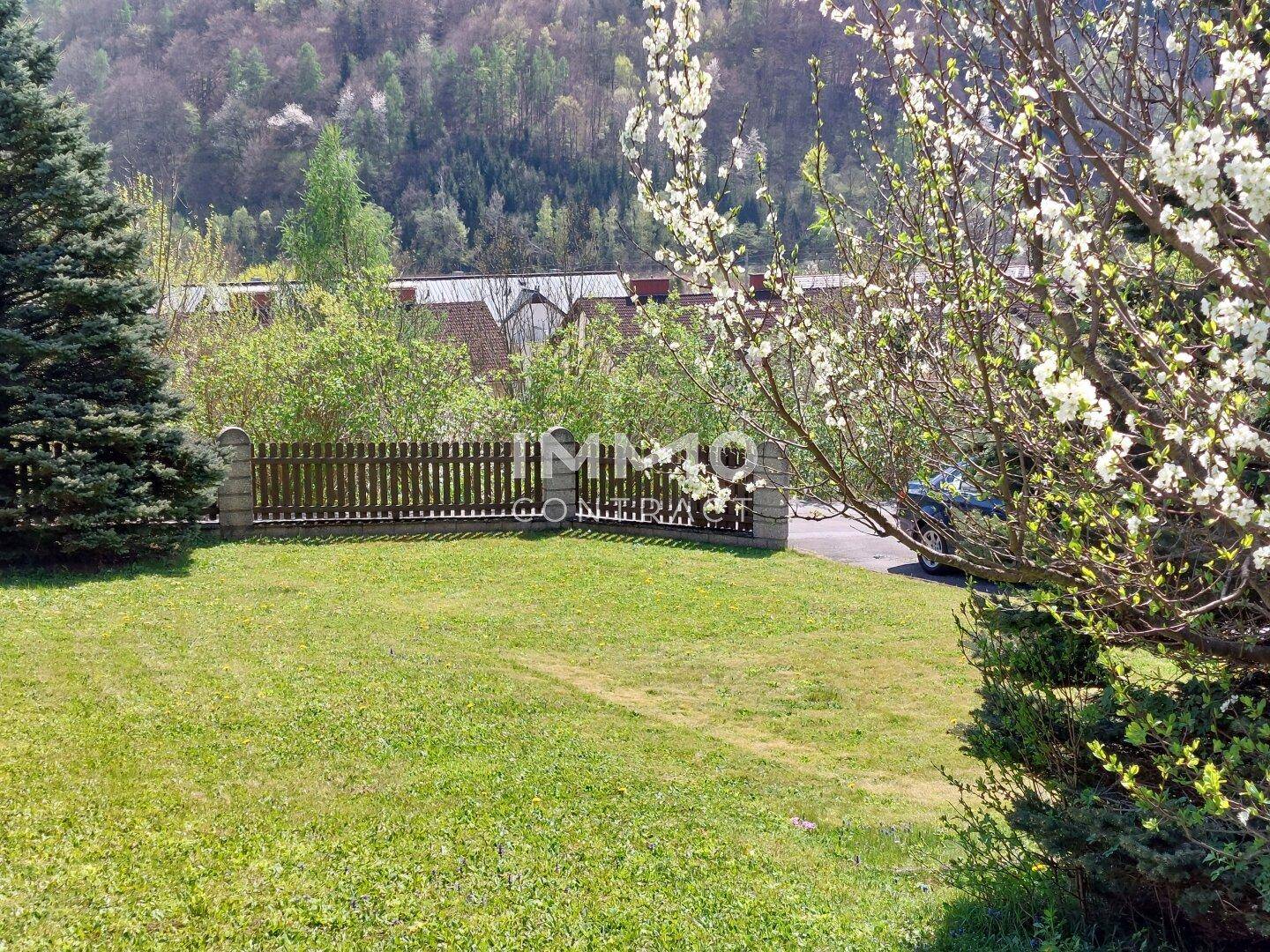 Gepflegter Gartenbereich mit Holzzaun und weitem Blick auf die umliegende Hügellandschaft.