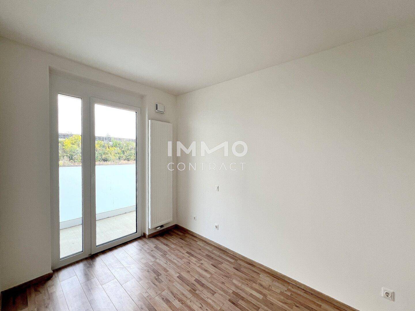 Helles Schlafzimmer mit Holzboden und direktem Zugang zum Balkon.