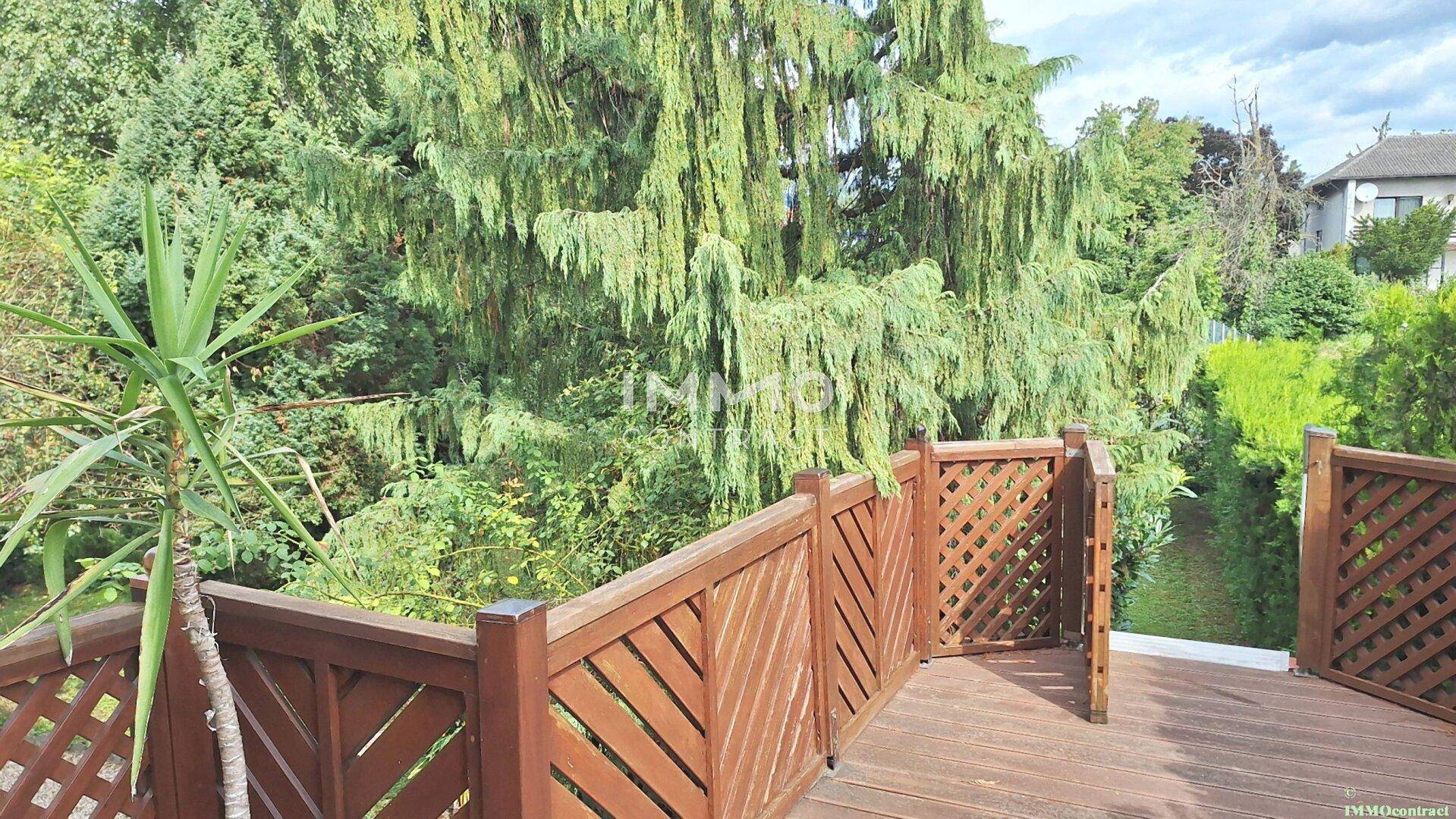 Holzterrasse mit rustikalem Geländer und Blick auf die umliegende grüne Landschaft.