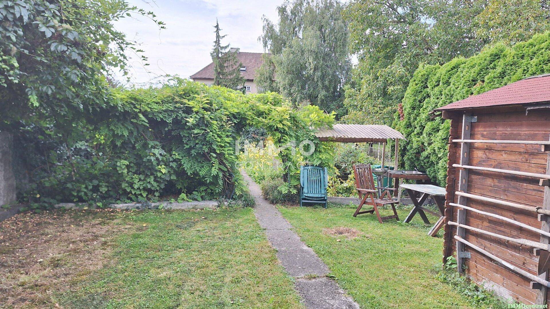 Idyllischer Gartenbereich mit Gartenhaus, Sitzgelegenheiten und üppiger Bepflanzung.