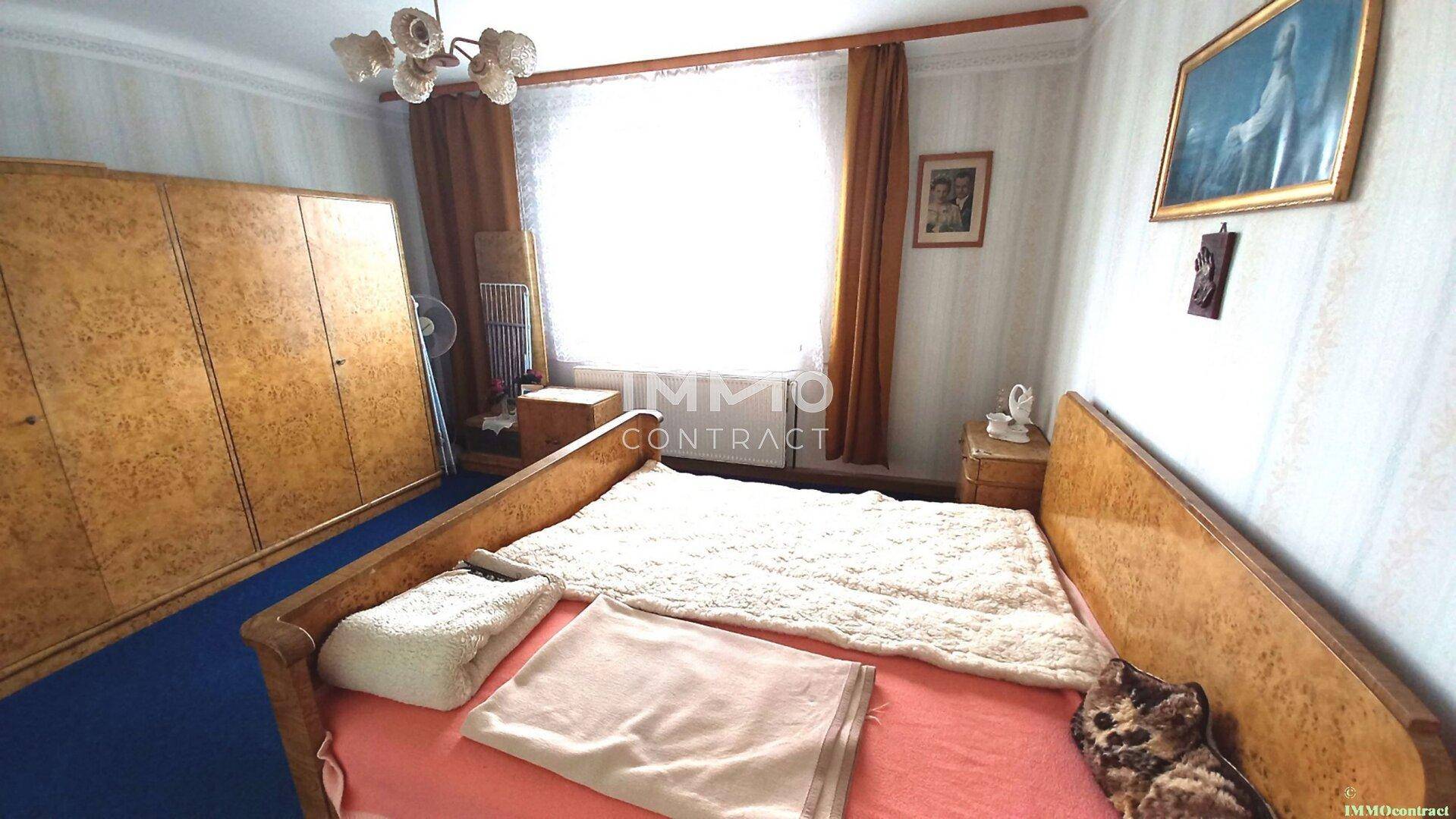 Schlafzimmer im Vintage-Stil mit Doppelbett, großem Kleiderschrank und gemusterter Tapete.
