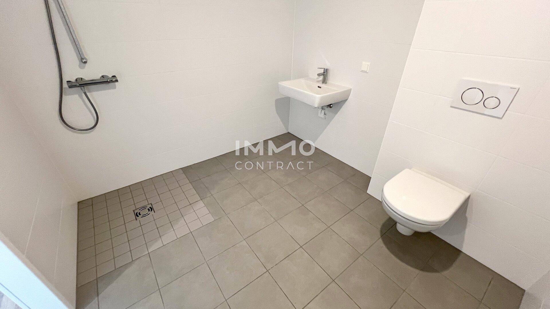 Modernes Badezimmer mit ebenerdiger Dusche, WC und Waschbecken.