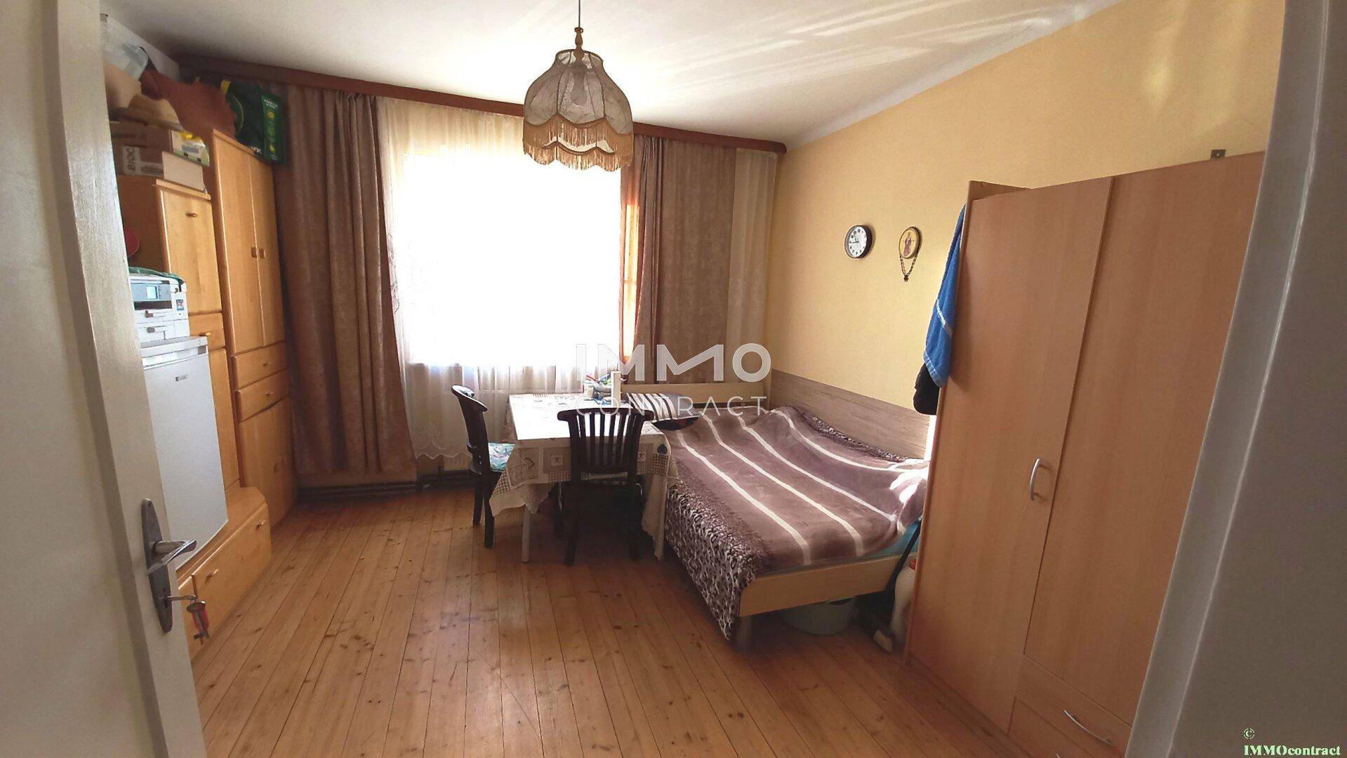 Helles Schlafzimmer mit Holzboden, Einzelbett und einem kleinen Esstisch.