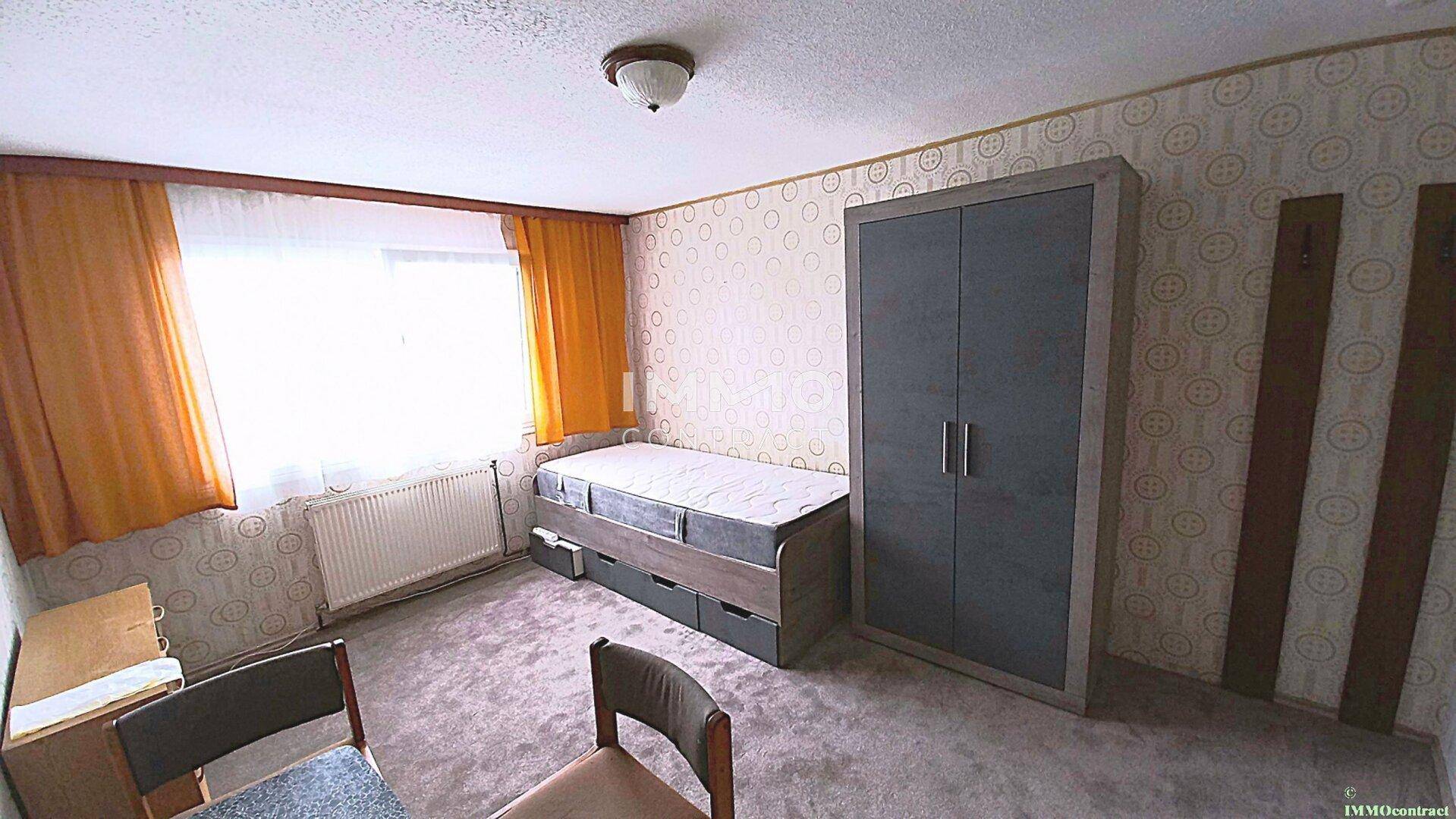 Schlafzimmer mit Teppichboden, Einzelbett und einem modernen Kleiderschrank.
