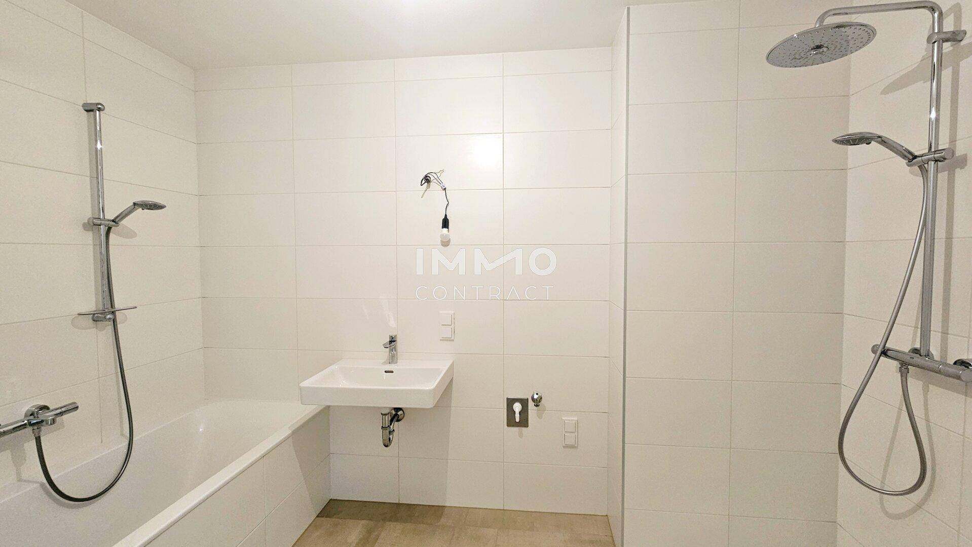 Modernes Badezimmer mit weißen Fliesen, Badewanne und separater Dusche, ausgestattet mit einem Einzelwaschbecken.