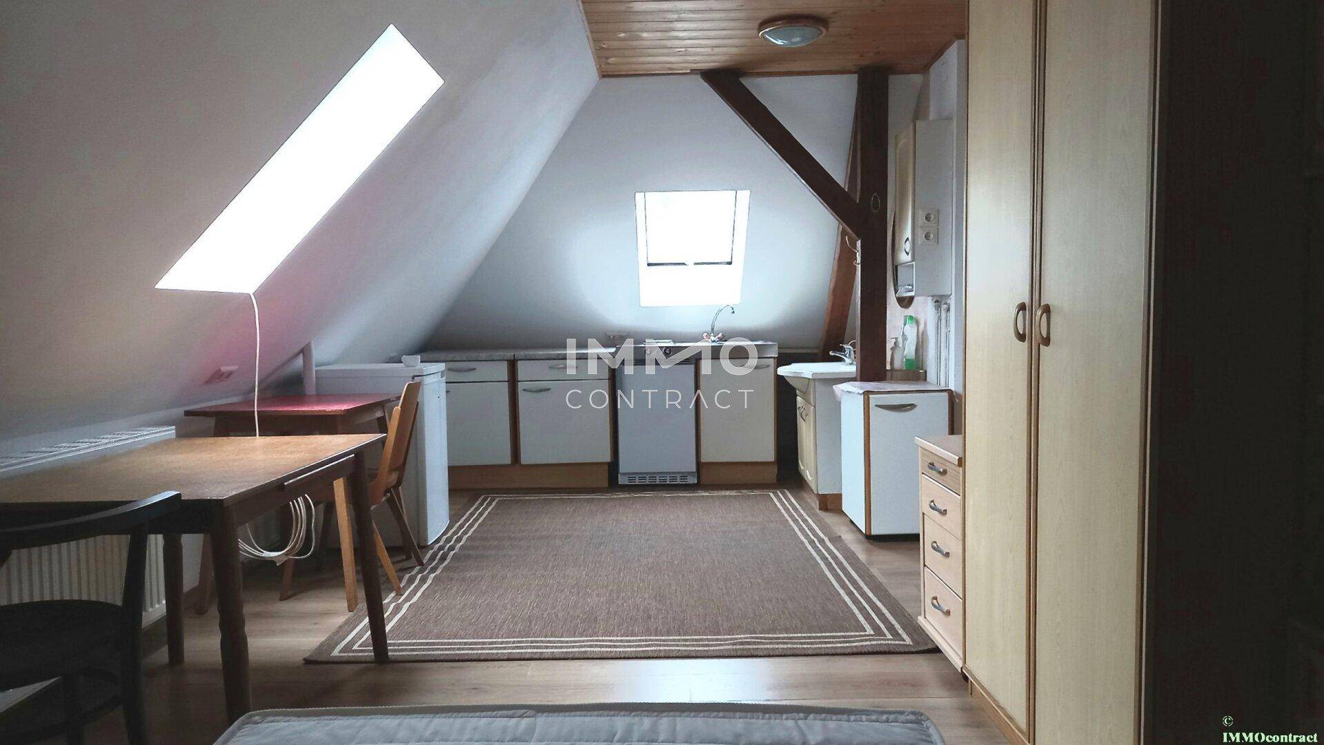 Dachgeschosszimmer mit Dachschrägen, Küchenzeile und Essbereich unter einem Dachfenster.